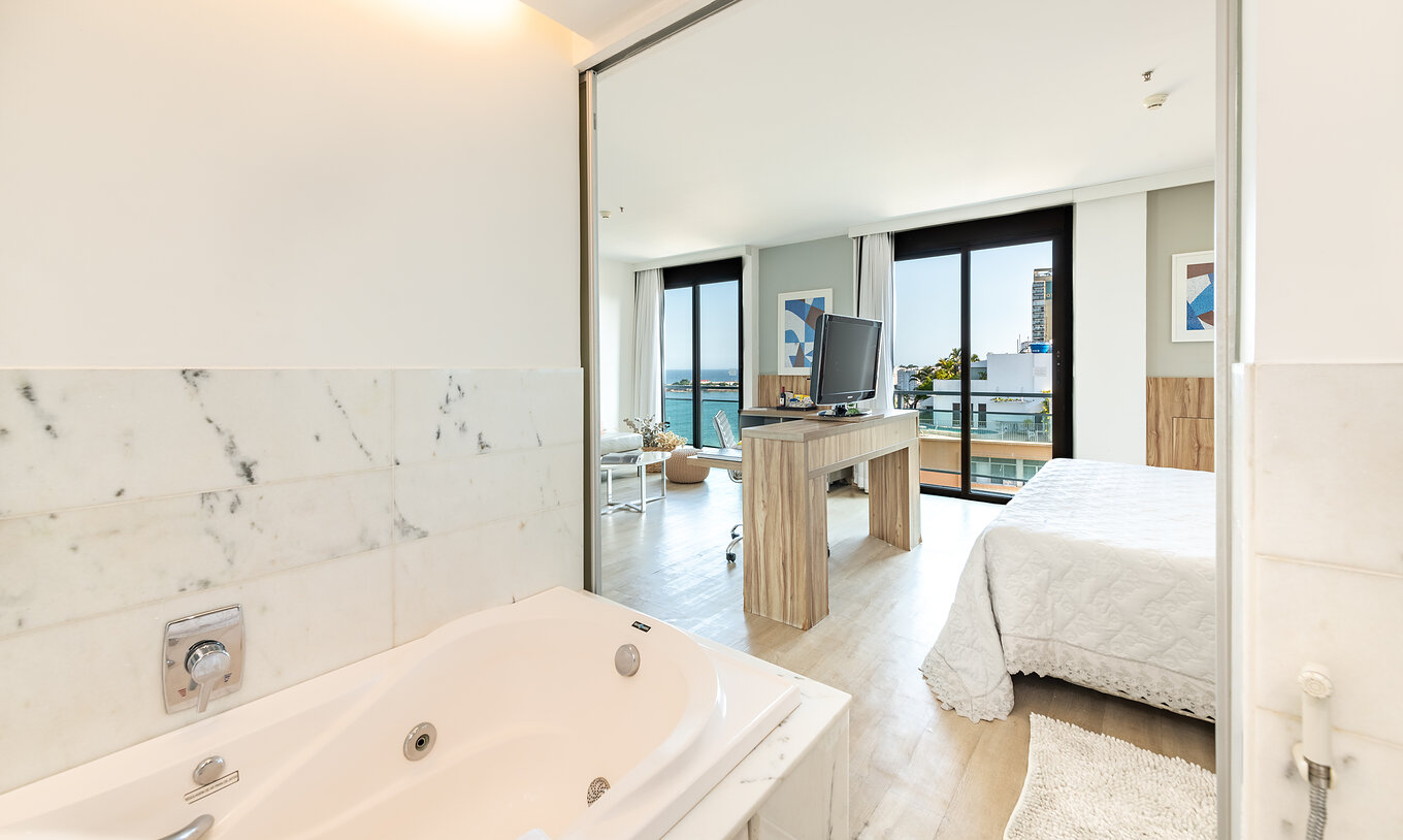 The Junior Suite of Pestana Rio Atlântica has a bathroom with a bathtub and a bedroom with television