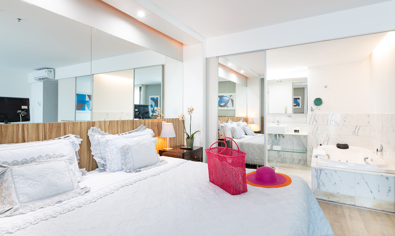 The Junior Suite of Pestana Rio Atlântica has a double bed, a mirror, and a bathroom with a bathtub