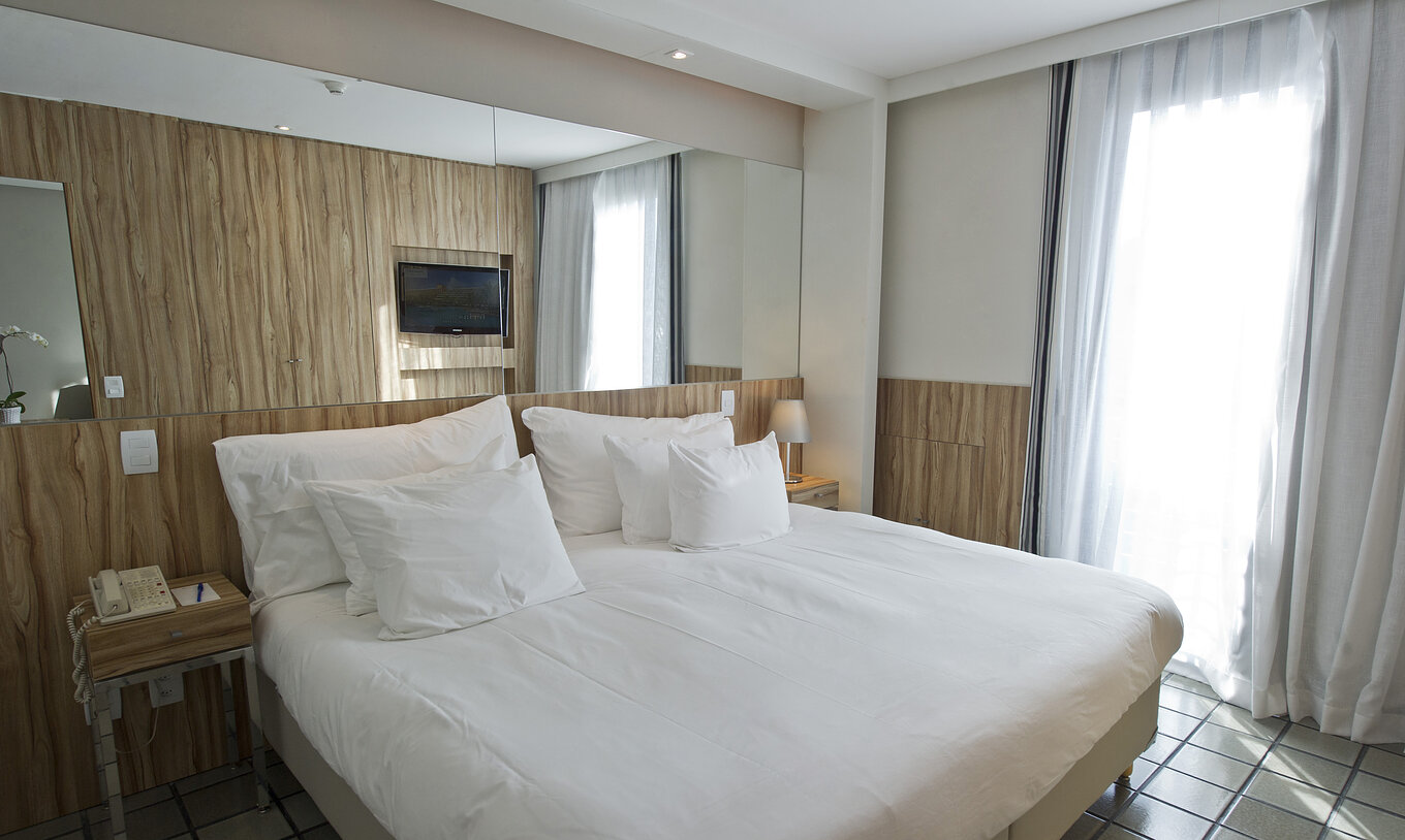 The Suite of Pestana Rio Atlântica has a double bed with a mirror on the headboard and two nightstands