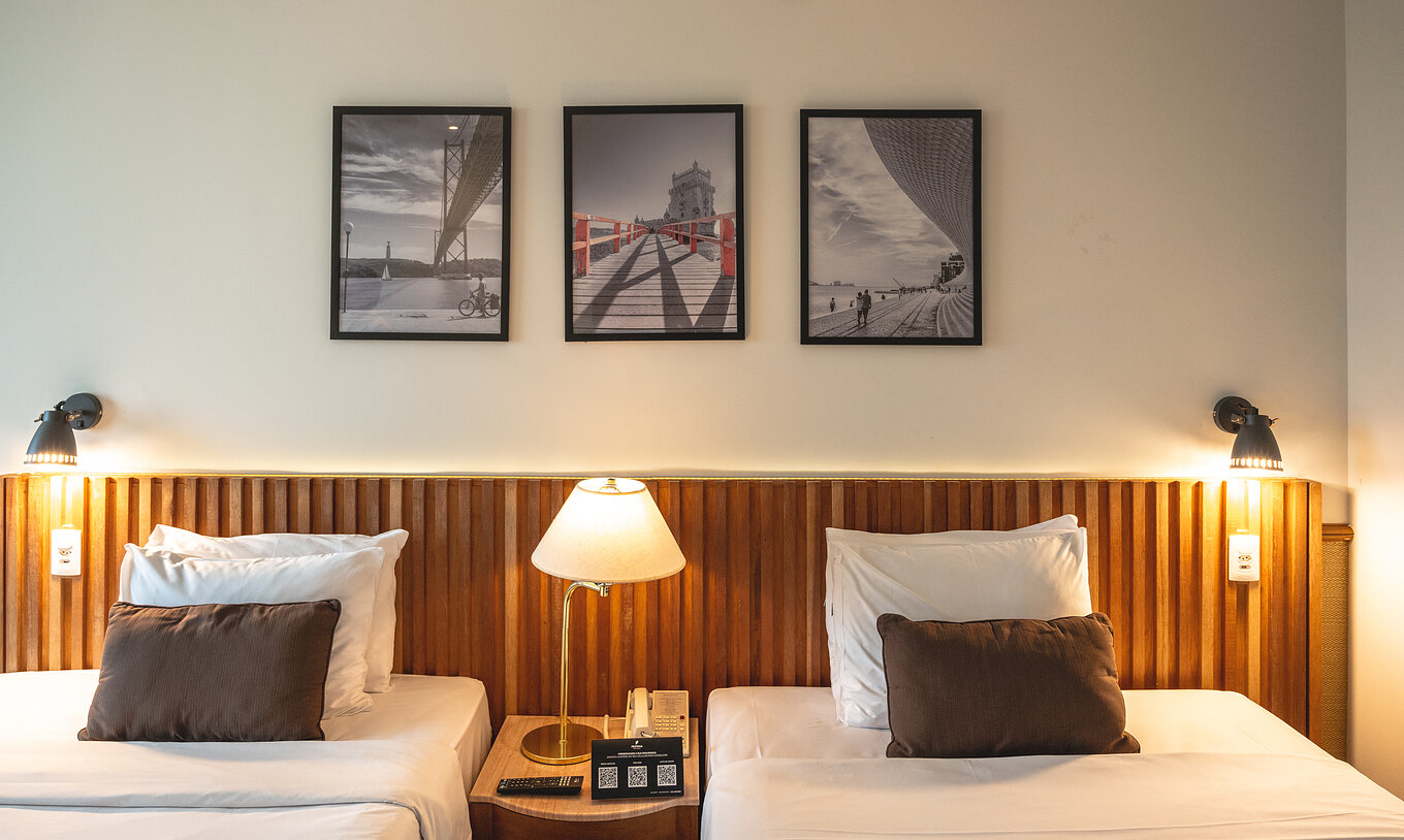 The Deluxe of Pestana São Paulo has two single beds, a wooden headboard, and a table in the center