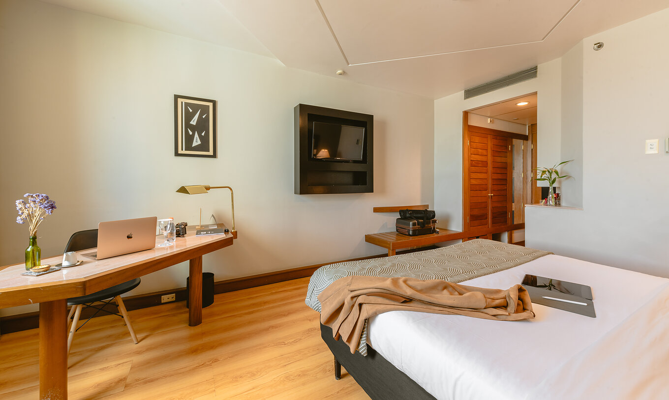 The Standard Room of Pestana São Paulo has a corridor at the entrance, a television at the foot of the bed, and a desk