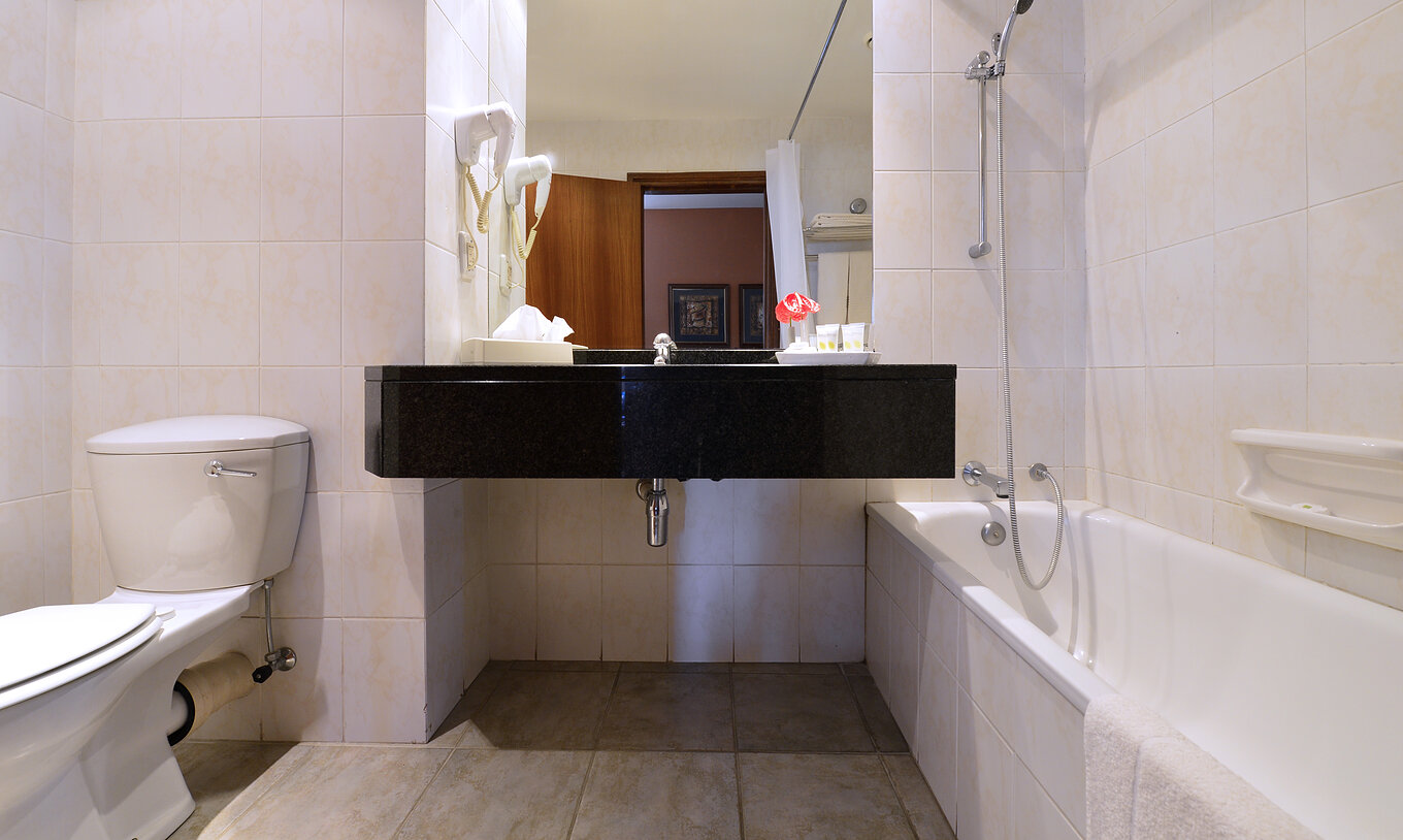 The Standard Double of Pestana Rovuma has a bathroom with bathtub with shower, sink with mirror, and a toilet
