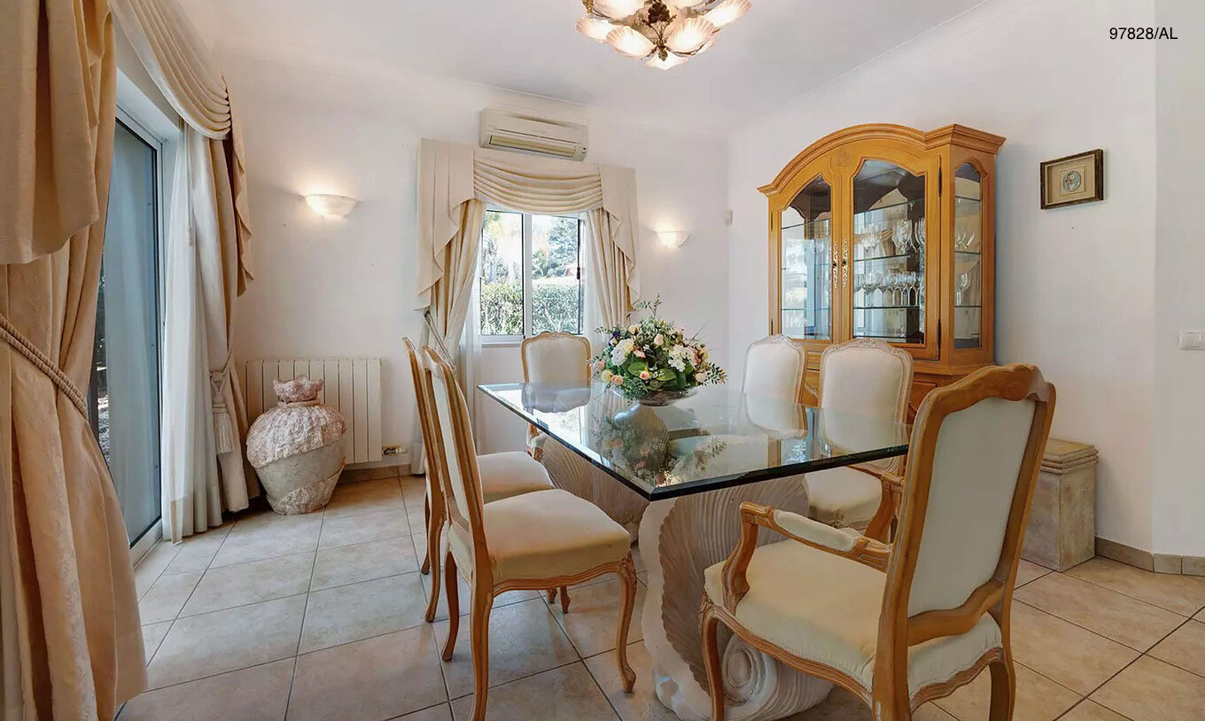 The Pestana Carvoeiro Golf V3 Standard Villa has a dining room with a glass table, chairs, and a cabinet