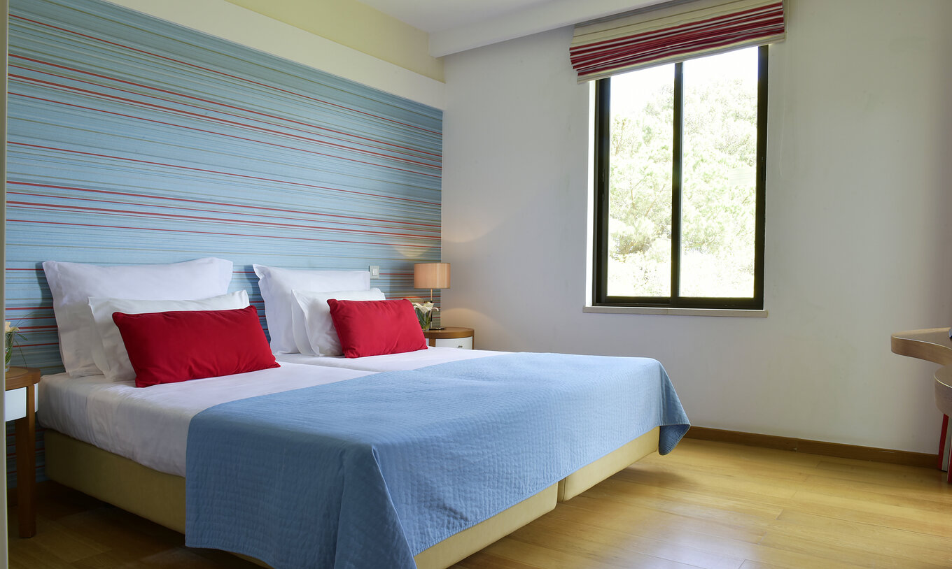 The Standard Suite at Pestana Dom João II has two single beds and a bedside table with a lamp