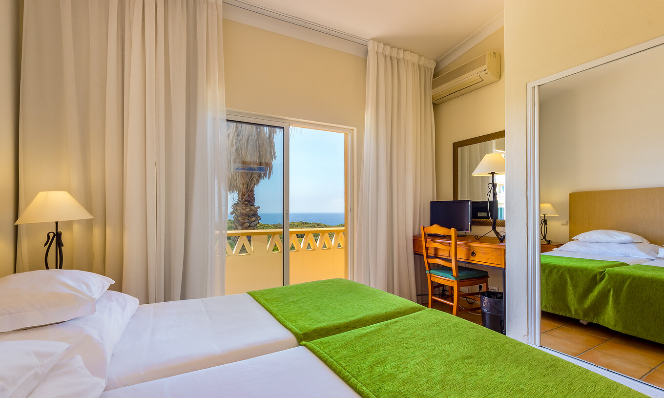 The T2 Apartment Premium do Pestana Palm Gardens has two beds with a green bedspread and a balcony with sea view