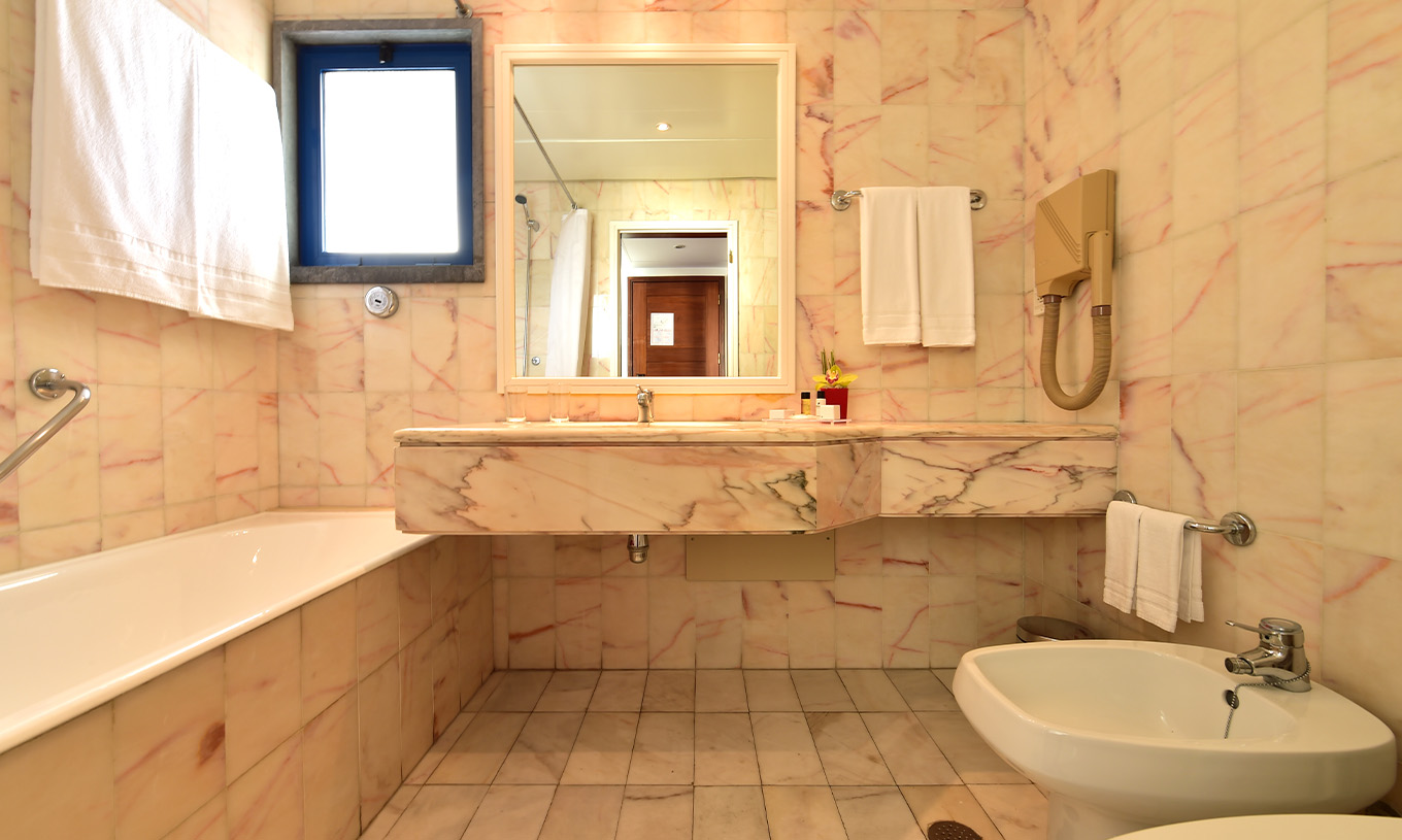 The Deluxe room at Pestana Cascais has a bathroom with a mirror, sink, and bathtub