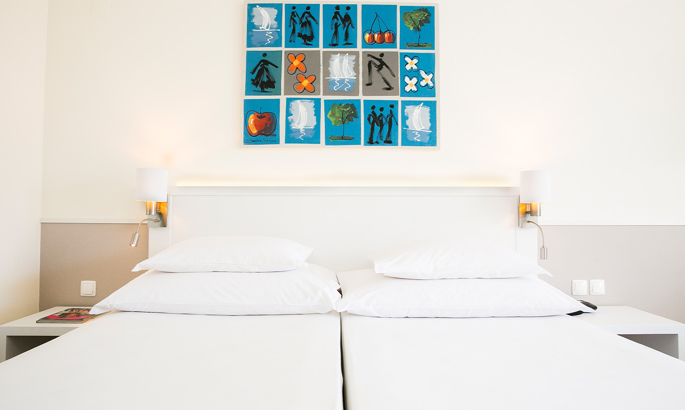 The Deluxe room at Pestana Cascais has two single beds, a bedside table with a lamp, and a picture on the wall