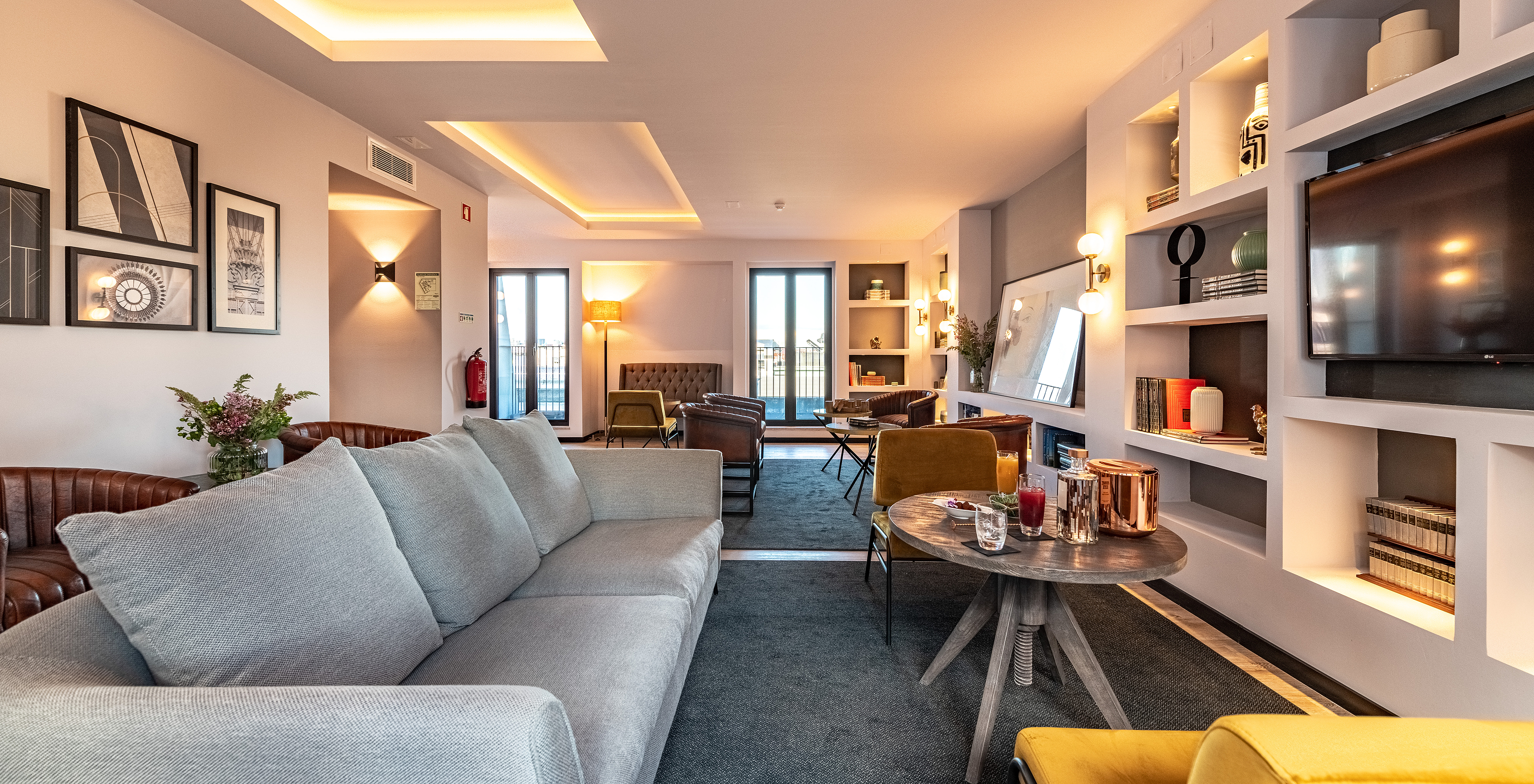 Lounge with sofas, chairs, tables, paintings, television, rugs and decor items with windows overlooking the city