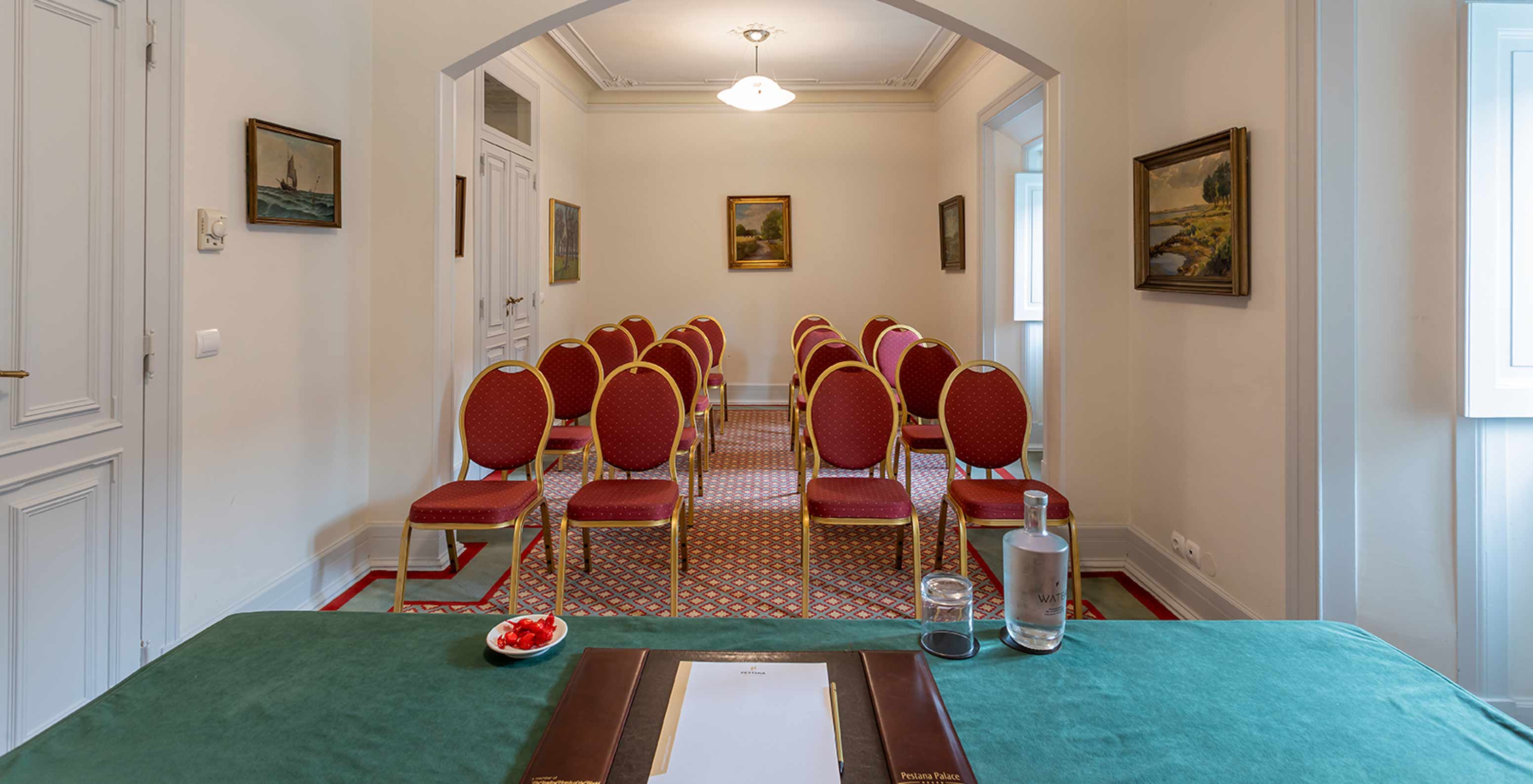 Pestana Palace Lisboa has a white meeting room in the palace with red armchairs and a green table