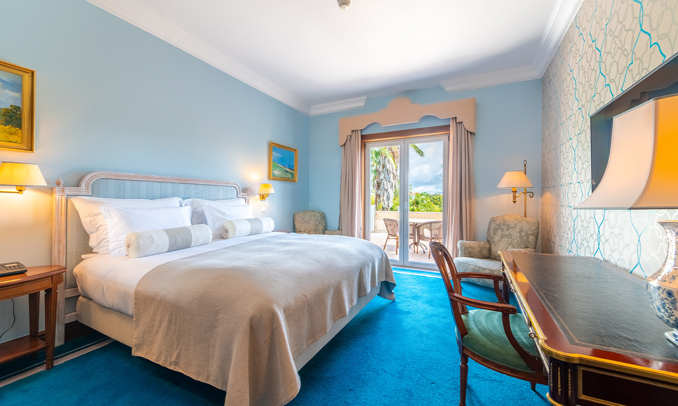 The Premium Balcony room at Pestana Palace Lisbon includes a double bed, light blue painted walls, and a window with curtains