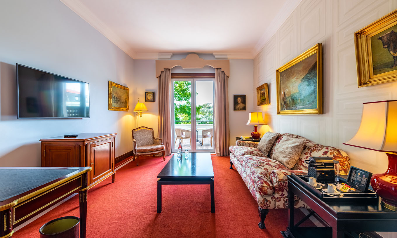 The Suite Collection at Pestana Palace Lisbon has a living room with a sofa, television and a window to access to the balcony