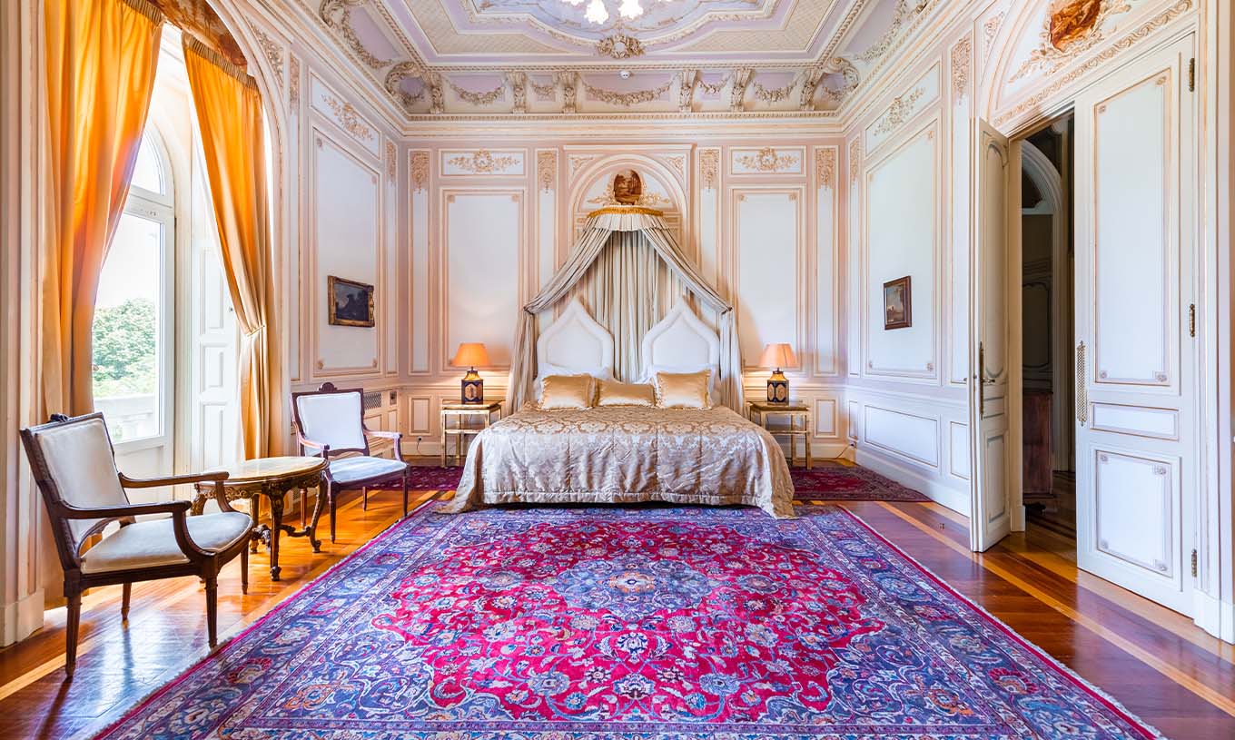 The Suite D. Carlos do Pestana Palace Lisboa has a luxurious room with a double bed and ceiling with ornate details