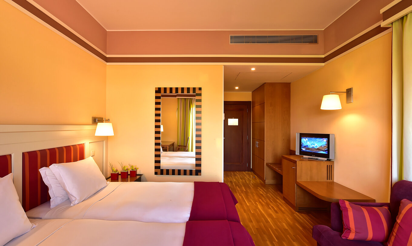 The Classic Double - Garden View of Pestana Sintra Golf has two beds, a mirror on the wall, a television, and a sofa