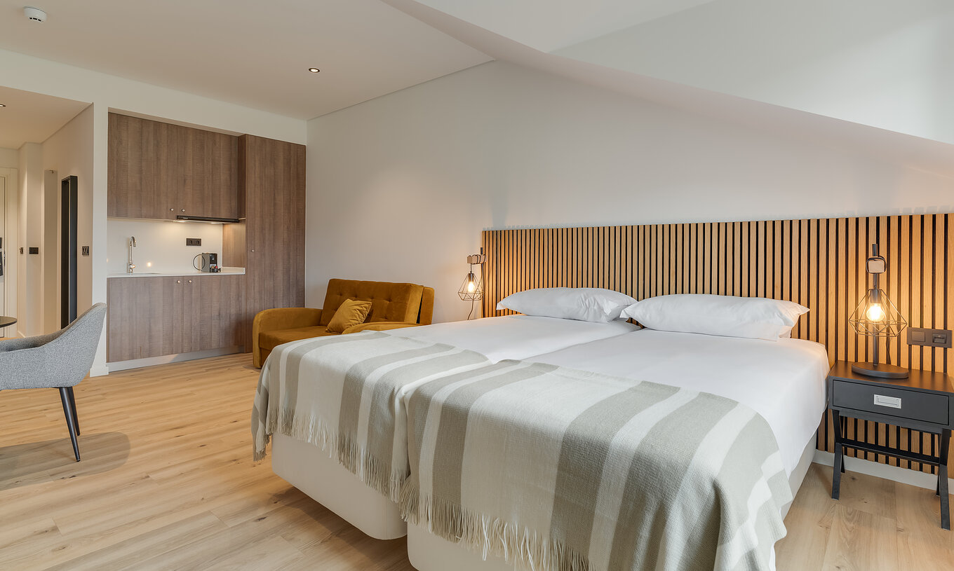 The Family - Clubhouse of Pestana Sintra Golf has two beds with wooden headboards, a sofa, and a kitchenette