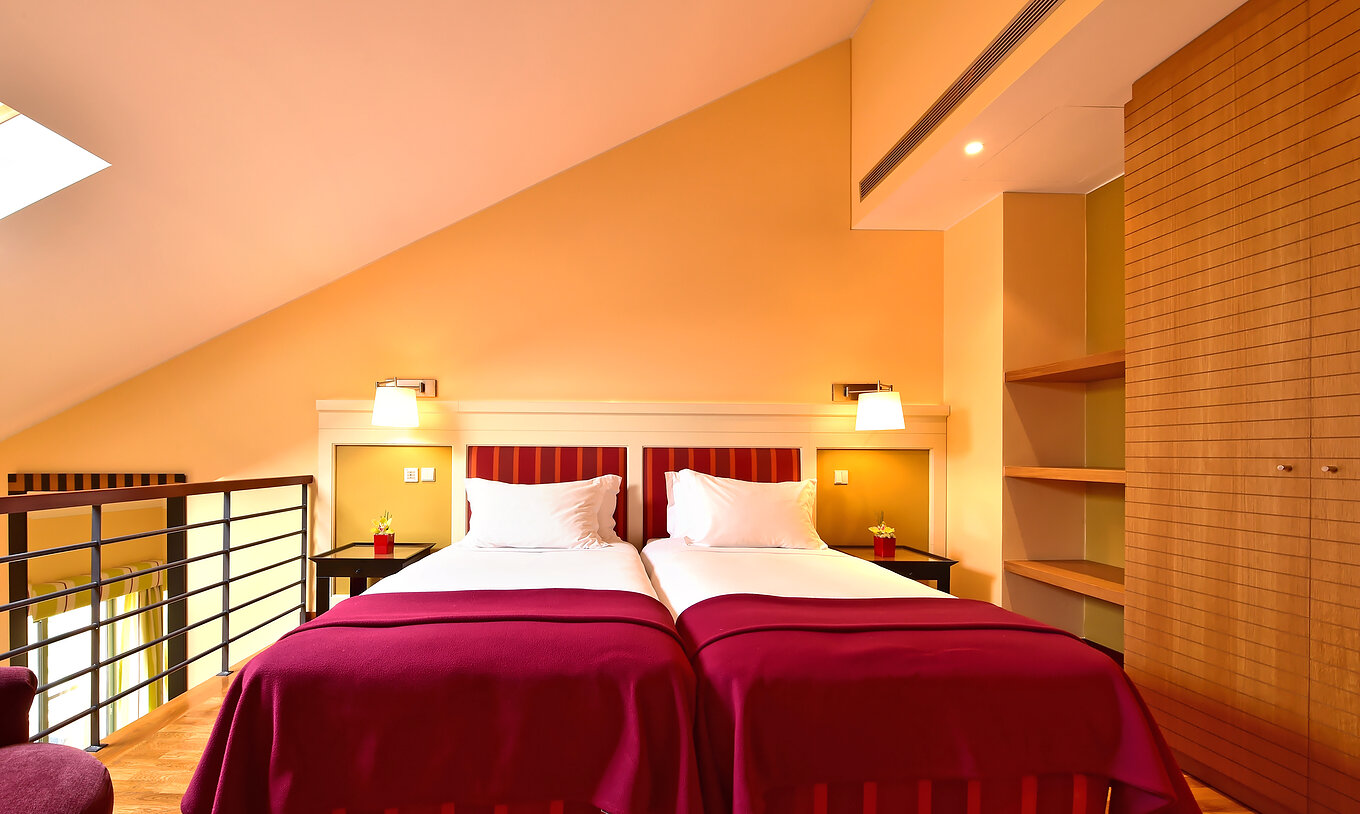 The Family Mezzanine Suite of Pestana Sintra Golf has a mezzanine with two beds, bedside table, wardrobe, and shelves