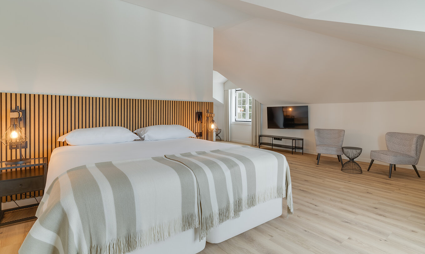 The Suite - Clubhouse of Pestana Sintra Golf has a double bed with wooden headboard, two chairs, and a television