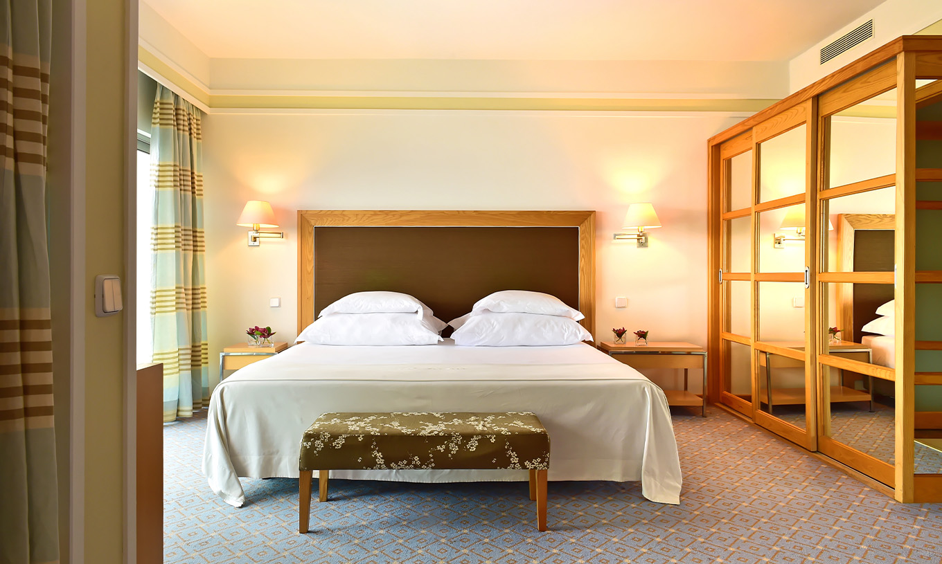The Superior Junior Suite at Pestana Carlton Madeira has a double bed with a bench at the foot and a wardrobe with mirrors