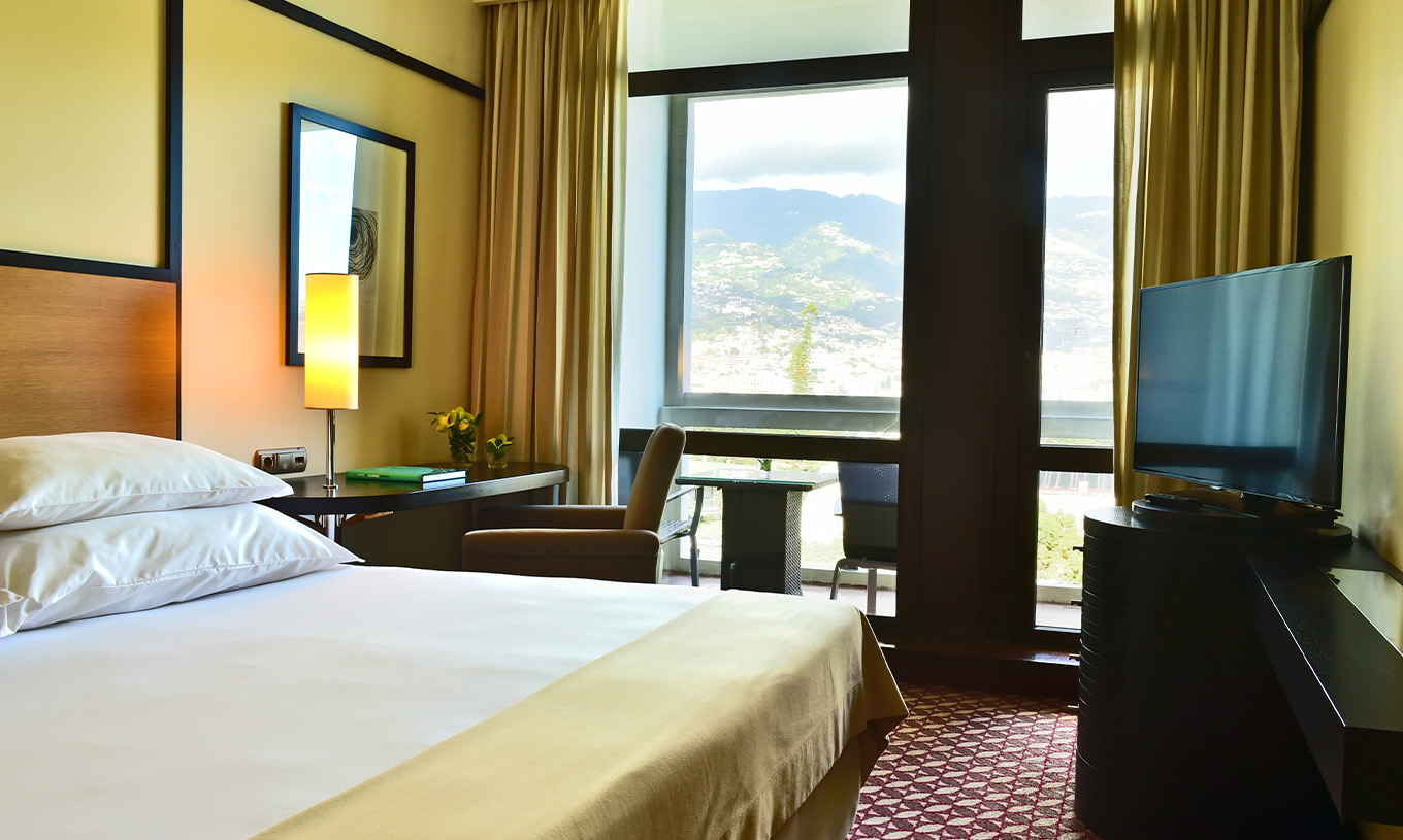 The Classic Garden View room at Pestana Casino Park has a double bed, a TV, a desk, and a balcony