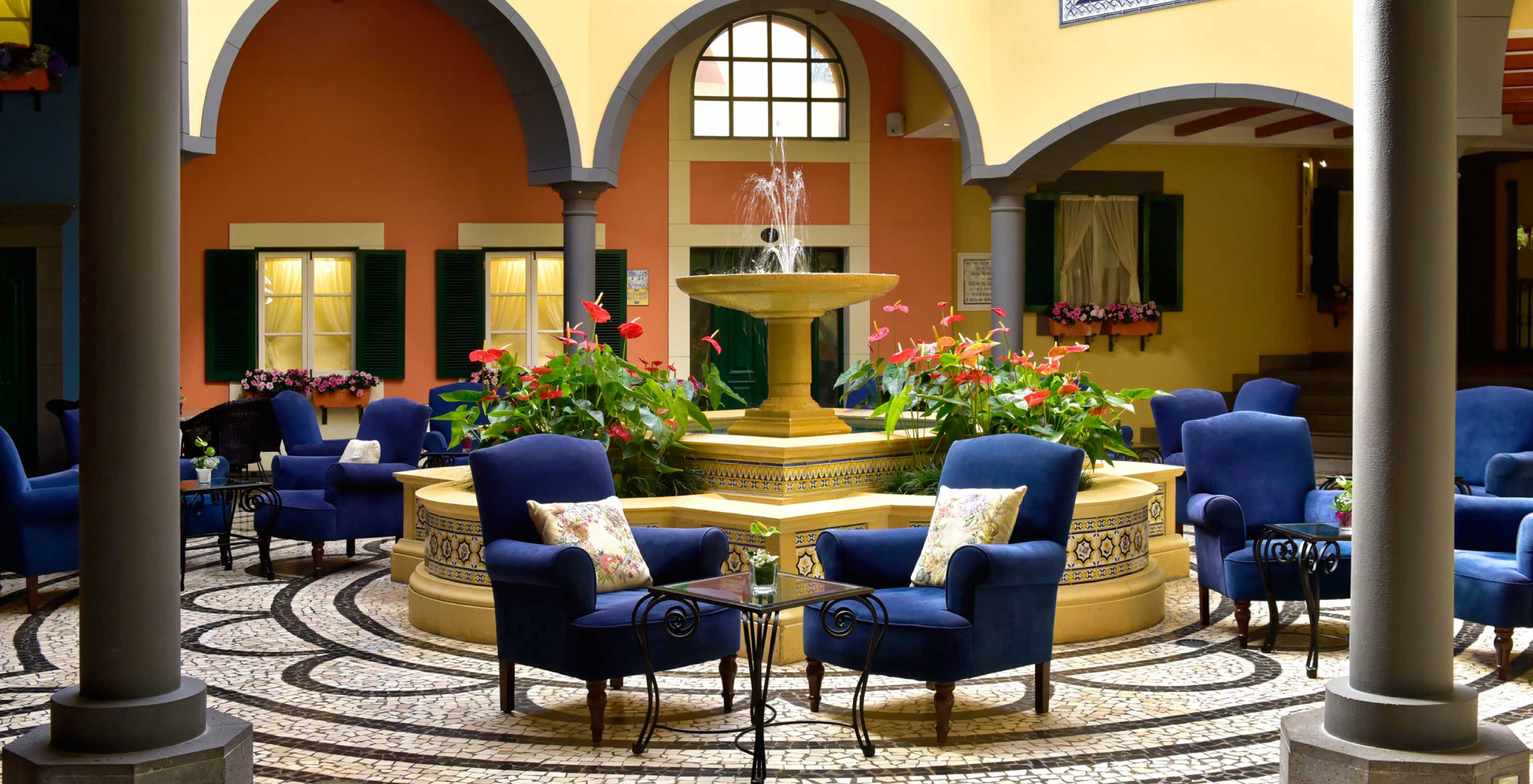 The bar A Fonte, at the Hotel de Charme in Madeira has a fountain with water and flowers and two blue armchairs