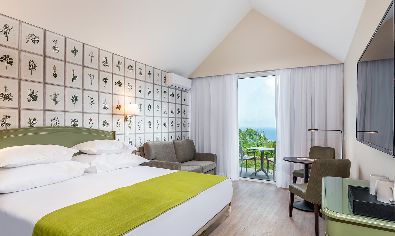 The Garden View Studio of Pestana Quinta do Arco has a double bed, sofa, side table, television, and balcony with sea view