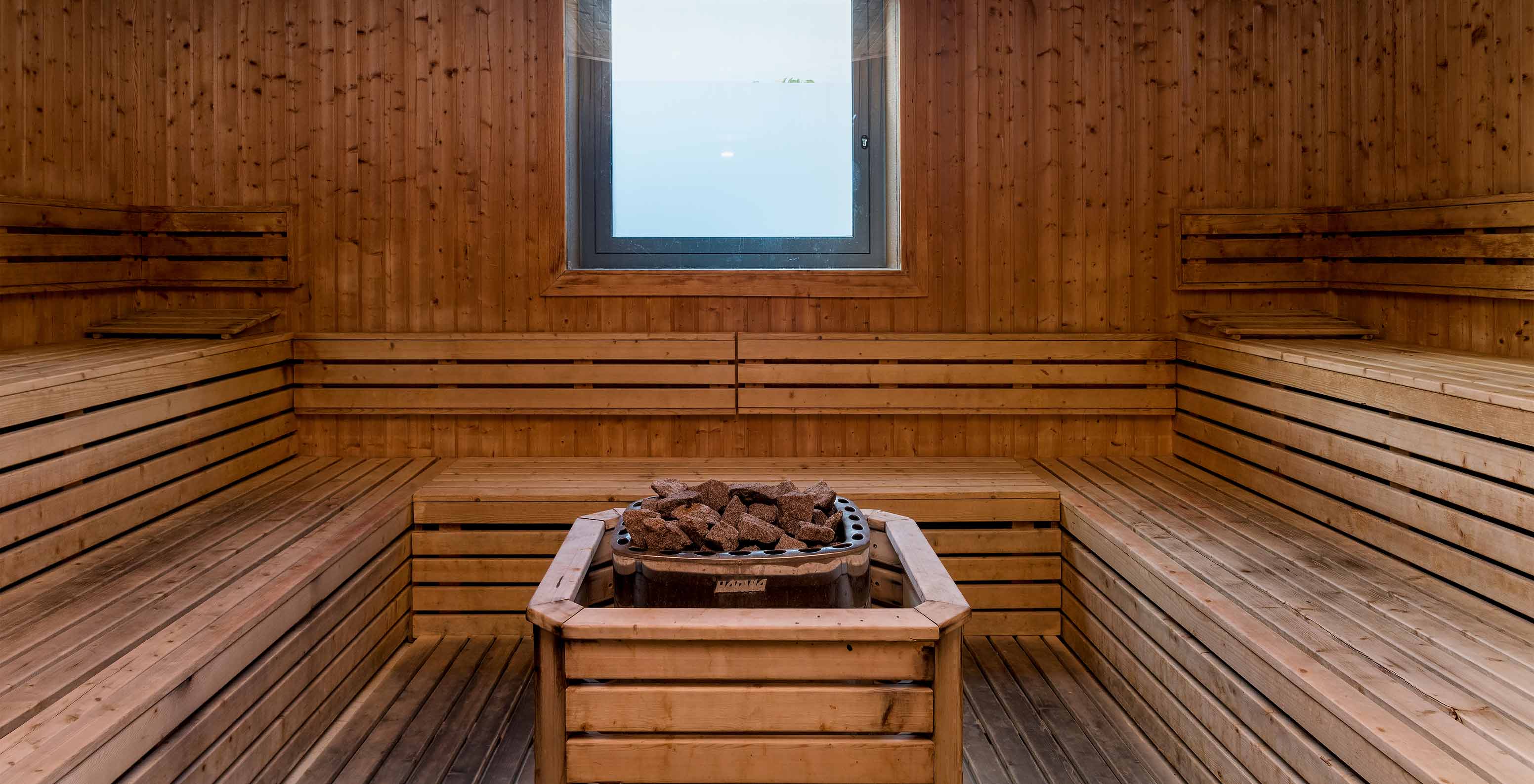Light wood sauna interior at Pestana Porto Santo, hot stones center, small window