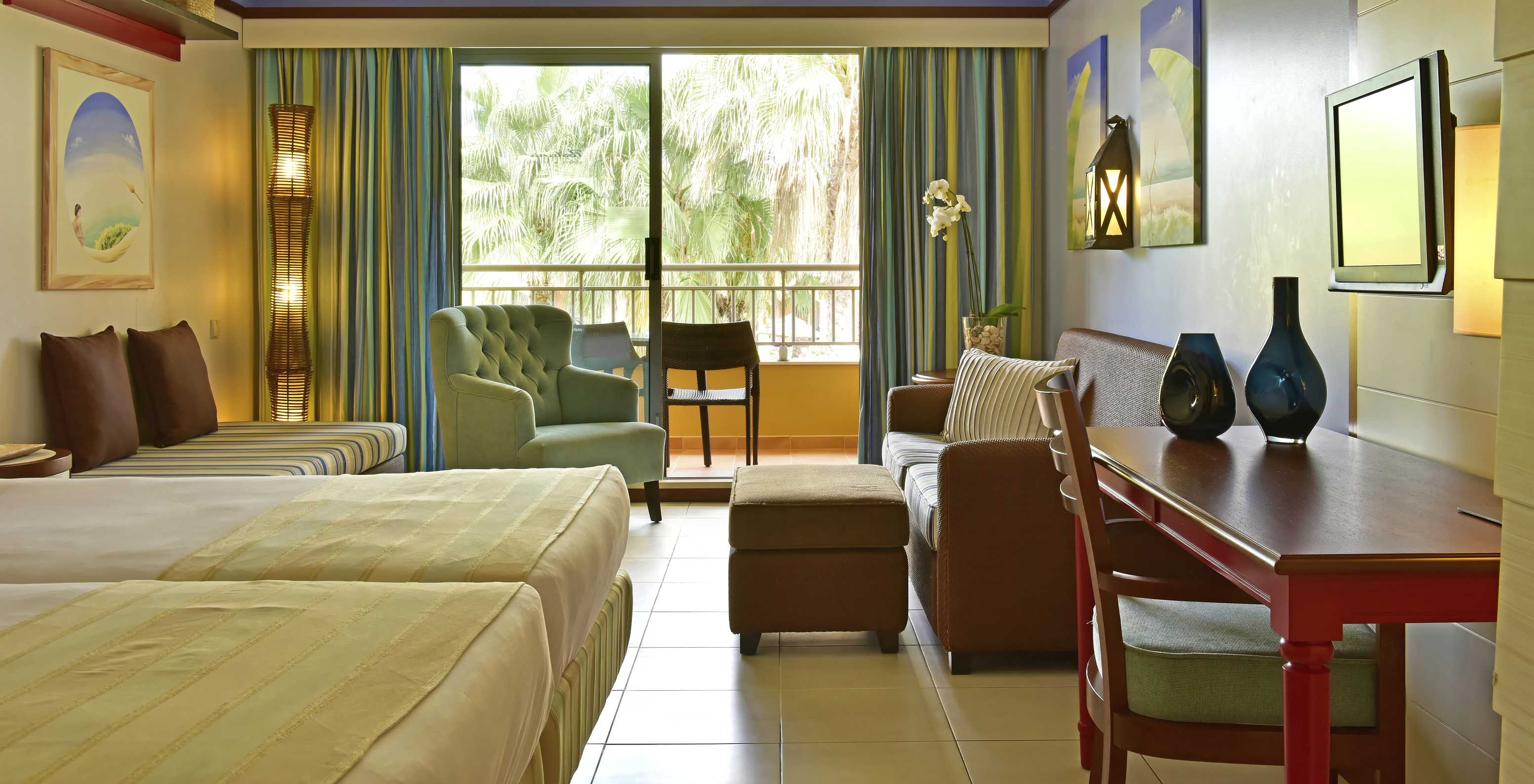 The Family Double of Pestana Porto Santo All Inclusive has two beds, a television, sofas, and a balcony with garden view