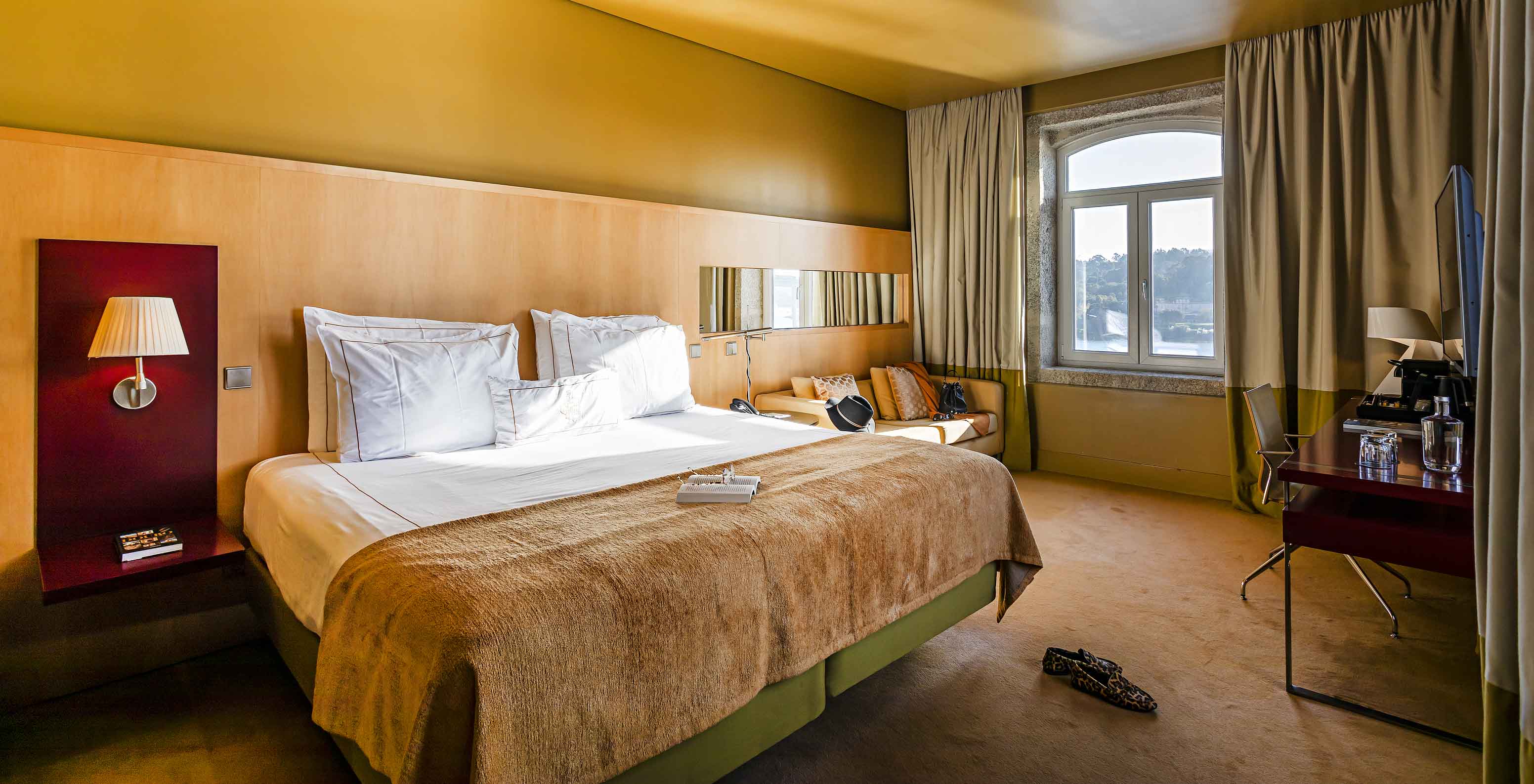 The Deluxe Grand View has a double bed and a stone-framed window with views of the Douro River
