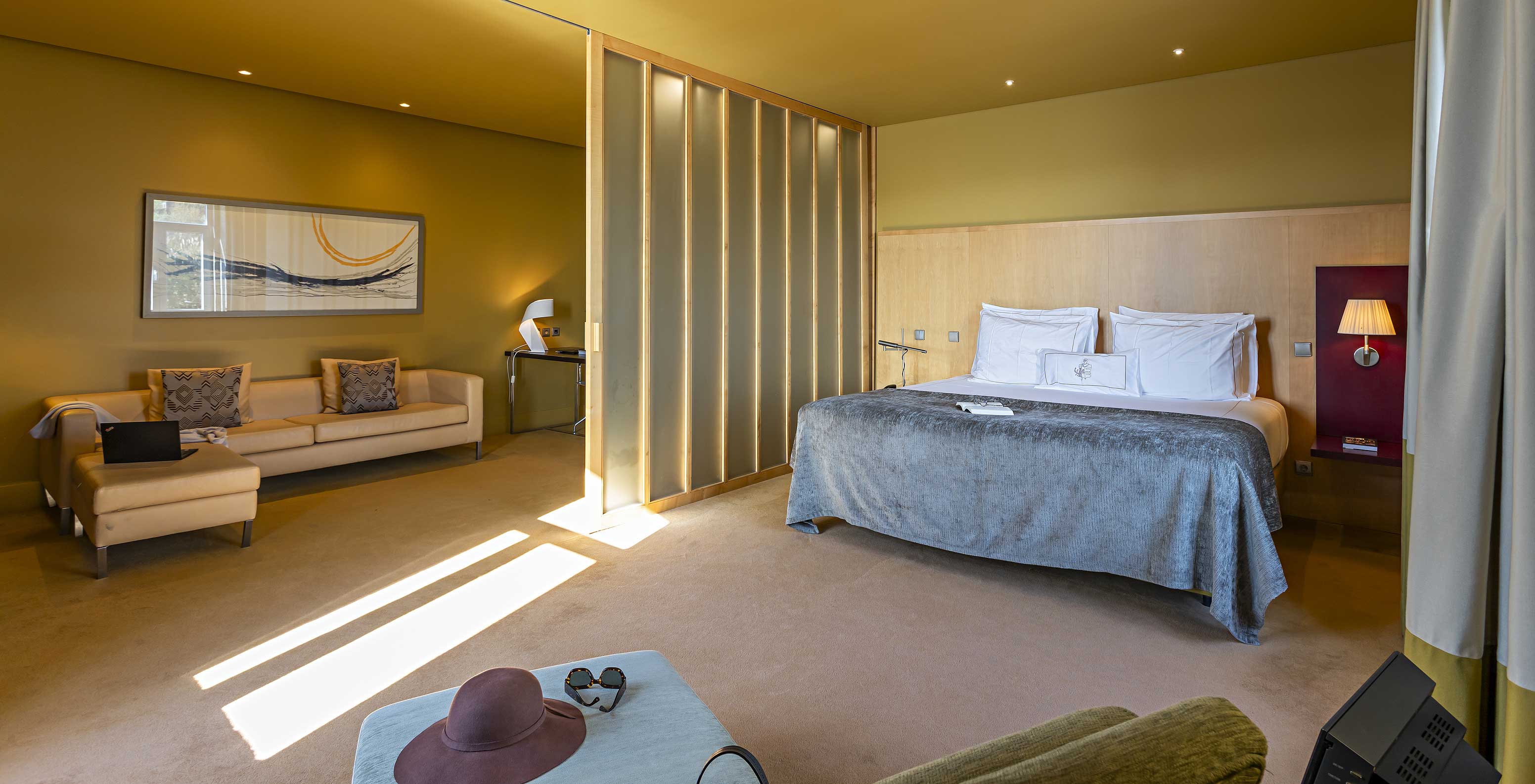 The Standard Suite has a large double bed with a grey blanket and a sofa