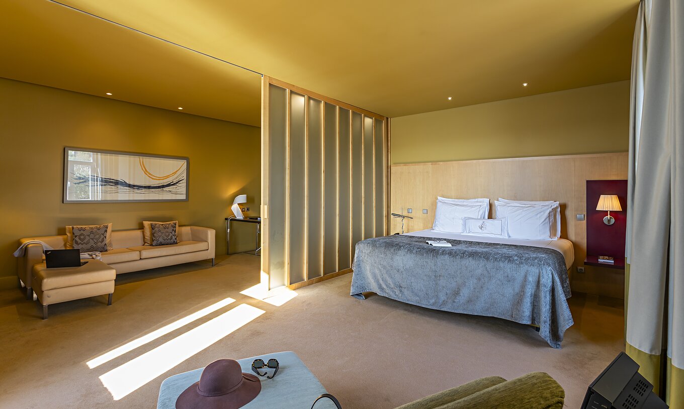 The Standard Suite has a large double bed with a grey blanket and a sofa