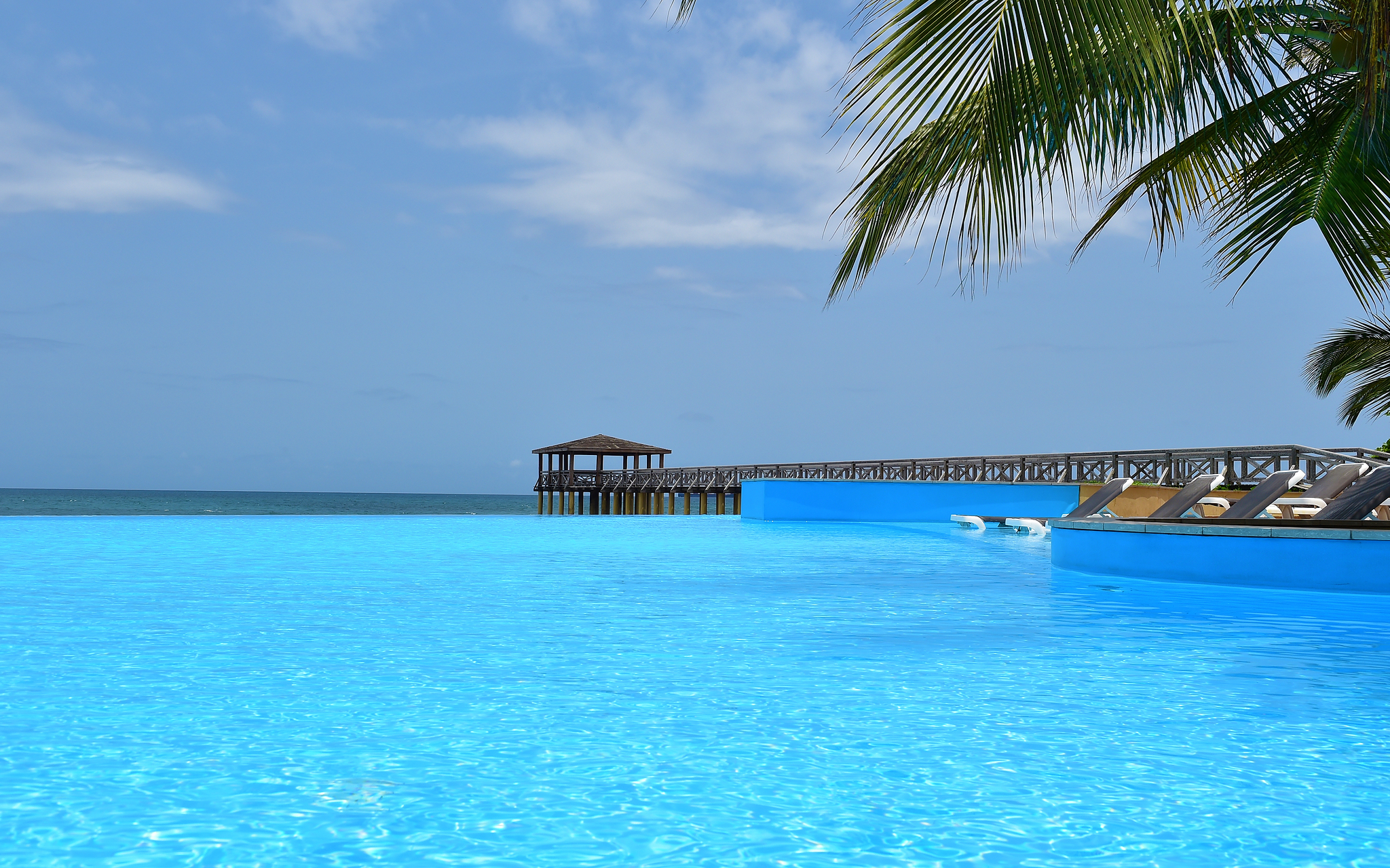 Paradise view of the pool at Pestana São Tomé merging with the crystal-clear sea, an idyllic tropical setting