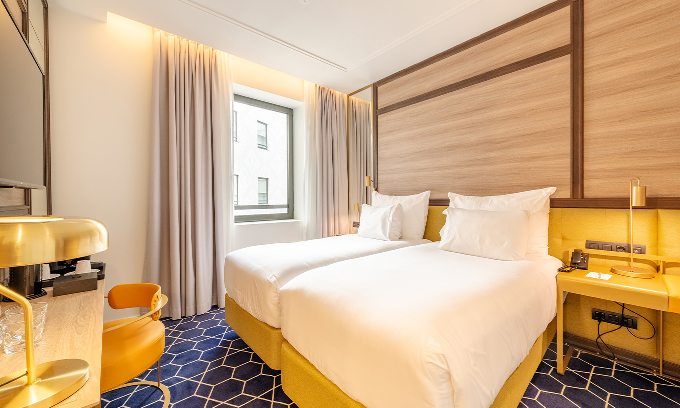 The Superior Room at Pestana CR7 Gran Vía Madrid features two beds, a chair, and a window facing the interior courtyard