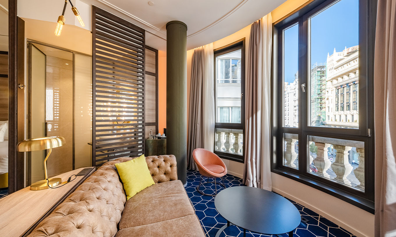 The Amazing CR7 Room at Pestana CR7 Gran Vía Madrid features a sofa, two tables, and large windows overlooking Gran Vía