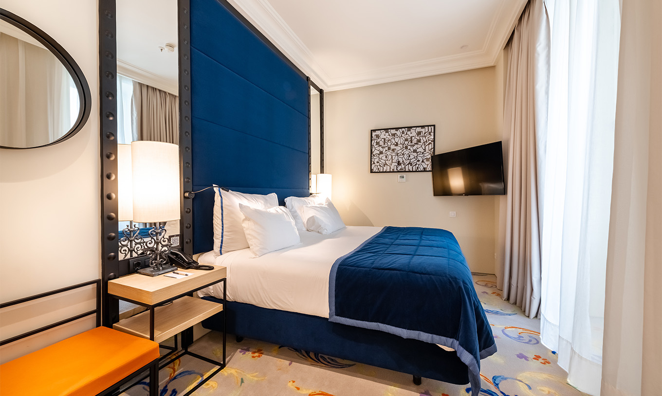 The Suite at Pestana Plaza Mayor Madrid has a double bed, bedside table, TV on the wall and window with curtains