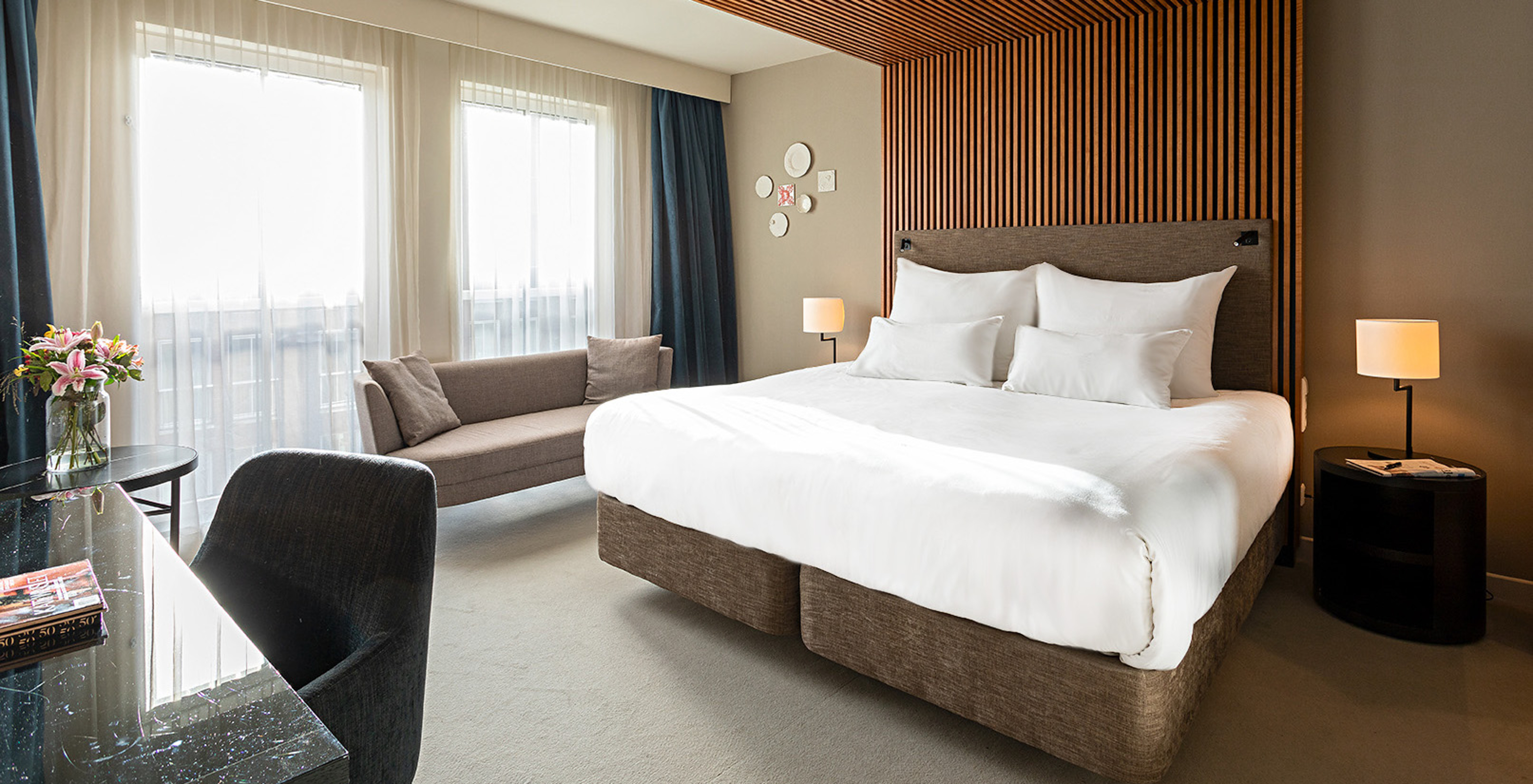 Superior room at Pestana Amsterdam Riverside has a double bed, a sofa, and a bedside table with lamp