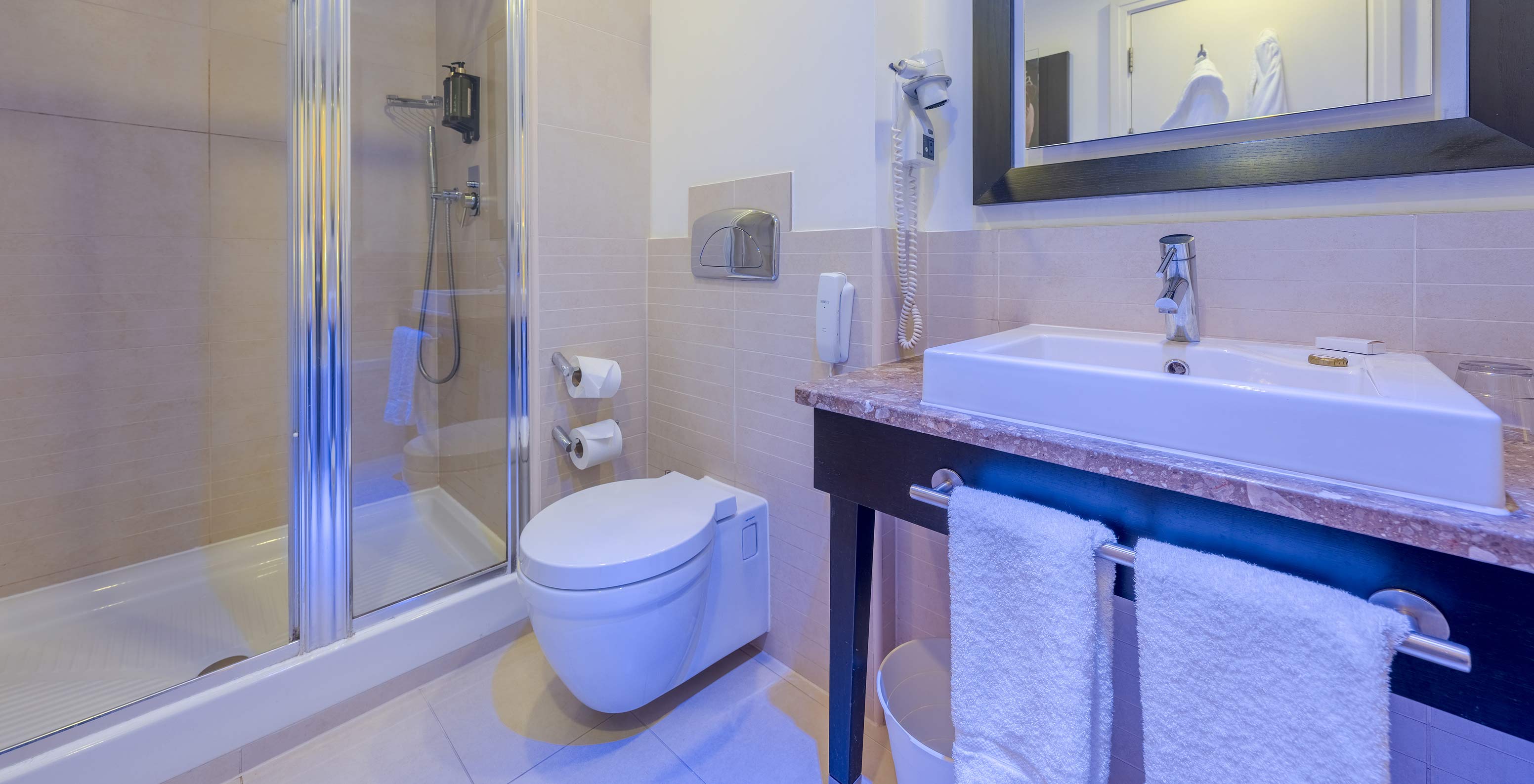 The Superior Twin at Pestana Chelsea Bridge has bathroom with glass-door shower, toilet, sink and mirror