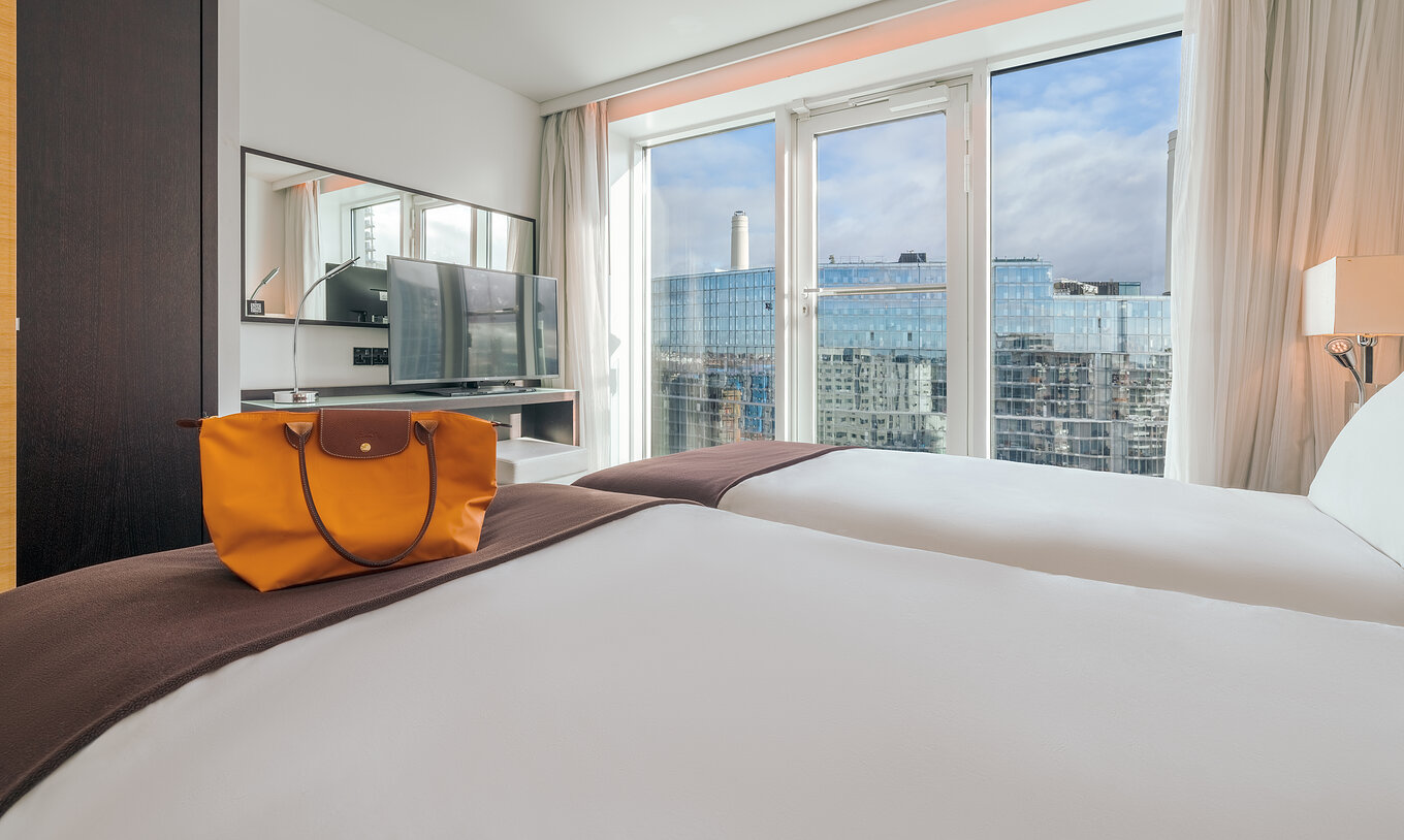 The Superior Twin at Pestana Chelsea Bridge has two beds, TV, mirror, city view window and curtains