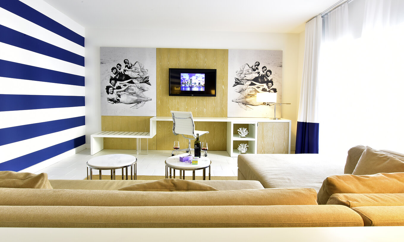 The Suite King with Balcony at Pestana Miami South Beach has a living room with a sofa with chaise longue, desk and TV