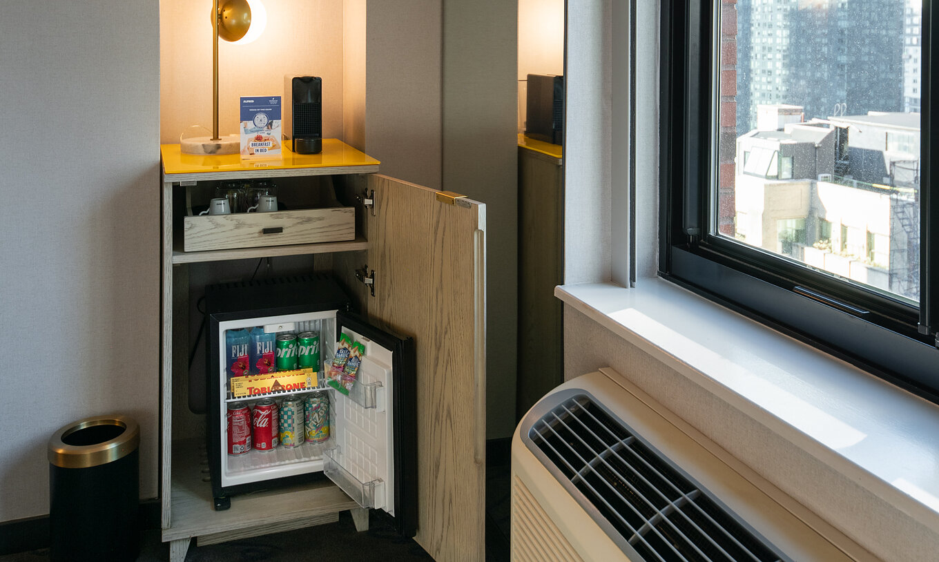 The Deluxe King Room ADA at Pestana CR7 Times Square has a wardrobe with a minibar by the window