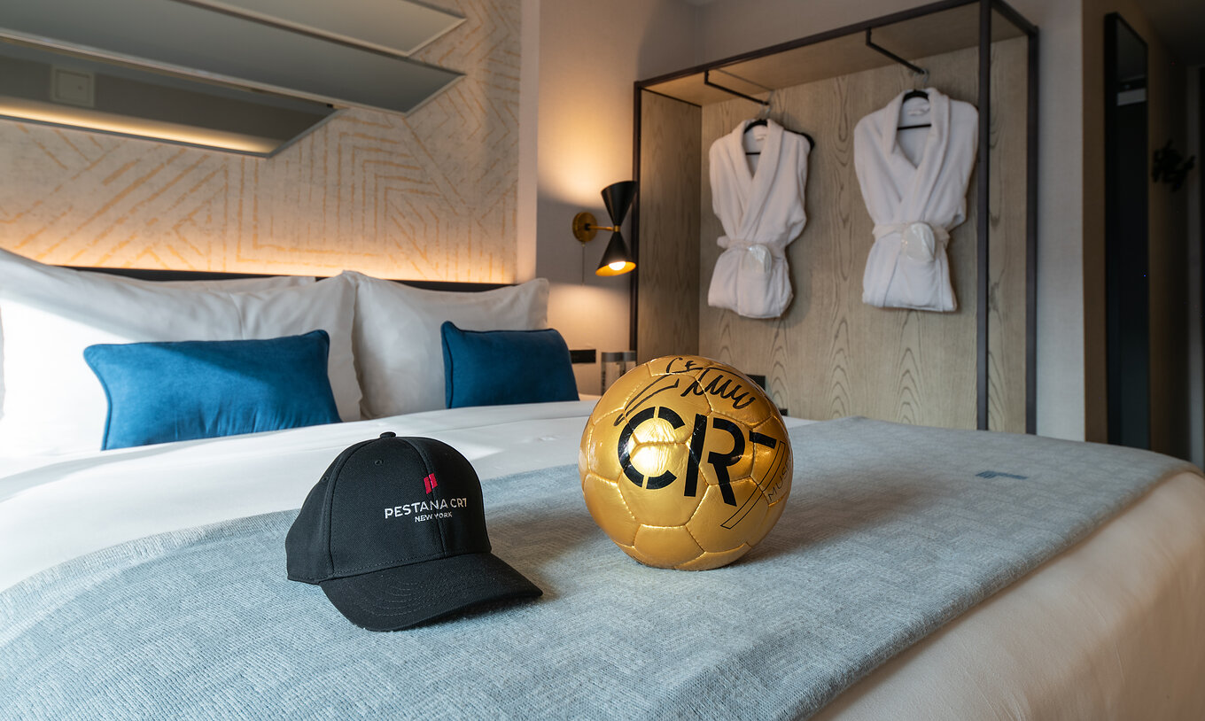 The Deluxe King Room at Pestana CR7 Times Square has a double bed with a CR7 ball and hat