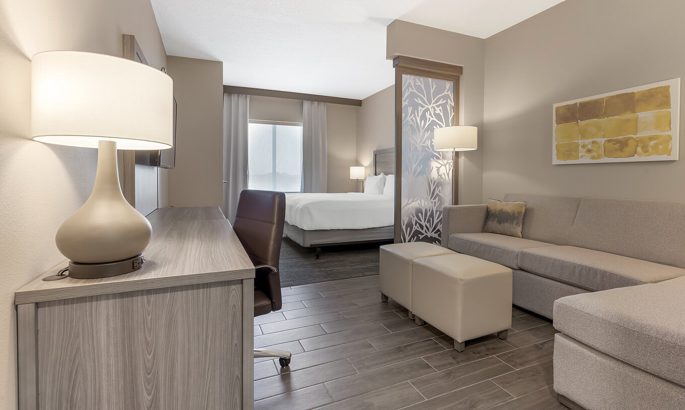 The King Master Suite at Pestana Orlando Suites Lake Buena Vista includes a double bed, desk, sofa, and lamp