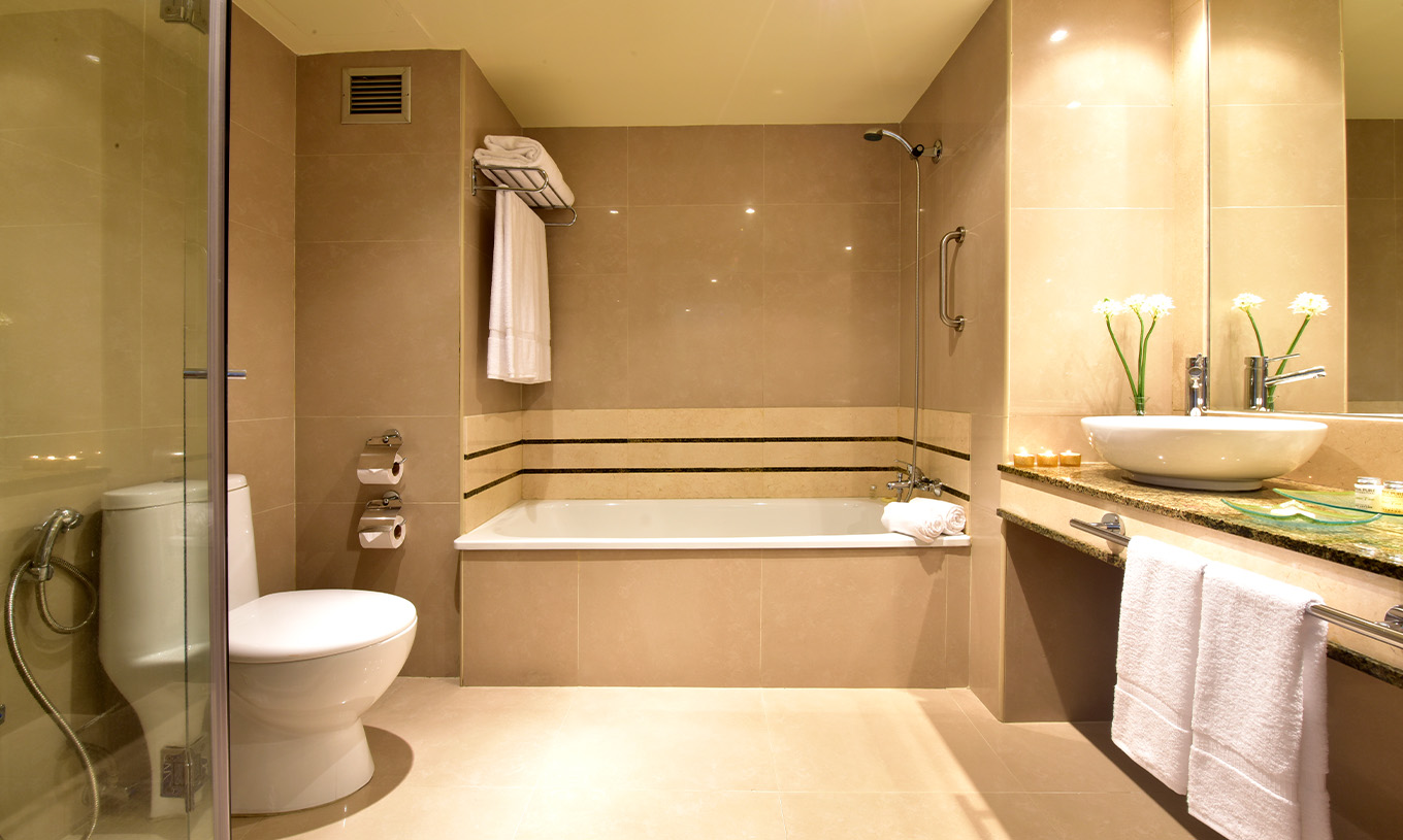 The Twin Superior Room at Pestana Caracas has a spacious bathroom with a bathtub, sink with mirror, and toilet