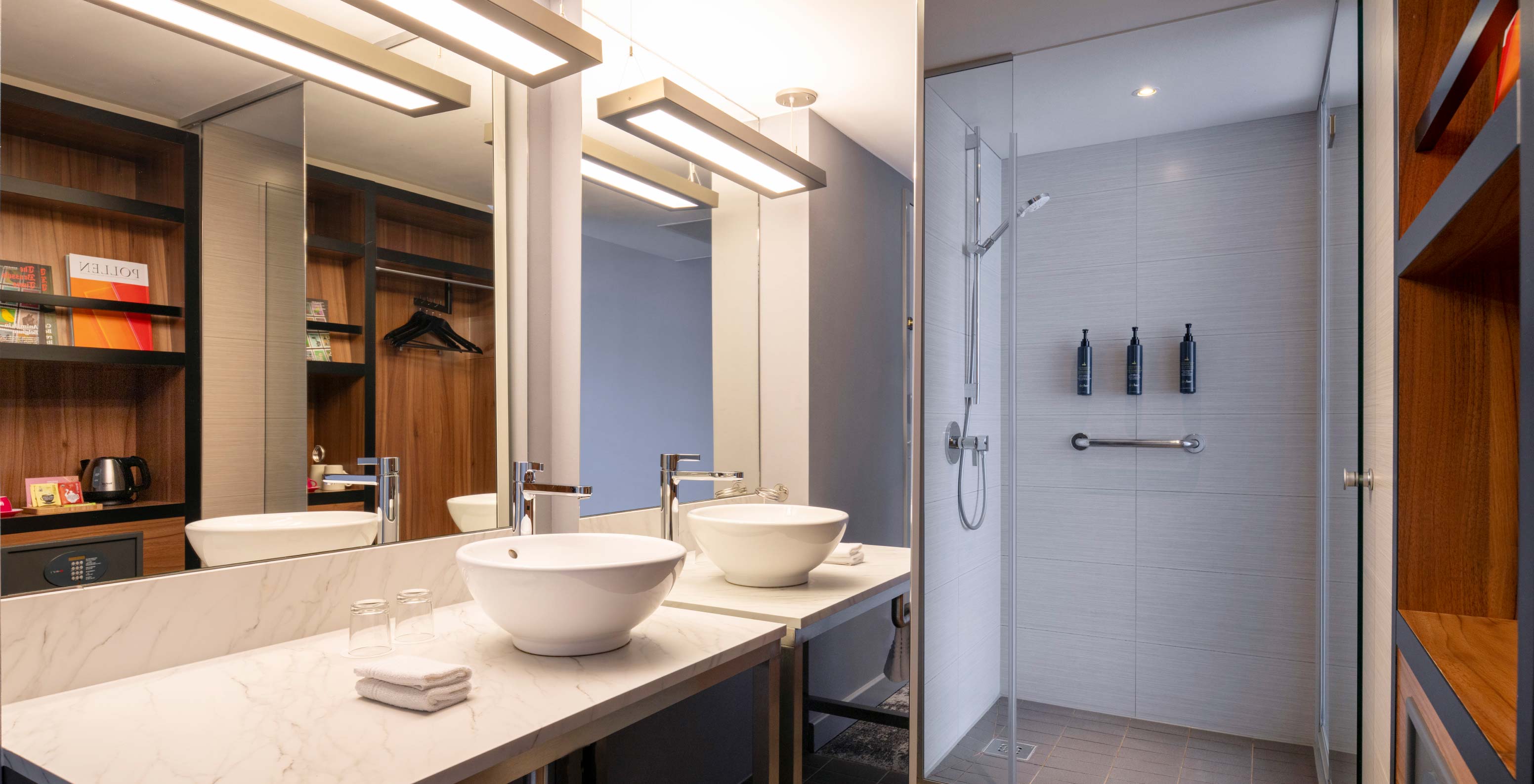El Standard Twin del Pestana Brussels Schuman tiene un baño con un lavabo, un espejo grande y una ducha