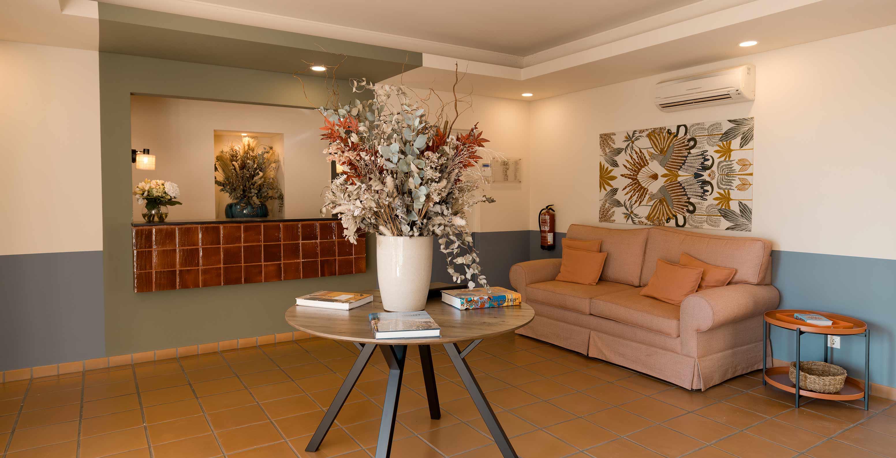 Recepción del hotel cerca de la playa con piscina, sofá naranja cómodo, mesa auxiliar y jarrón con flores