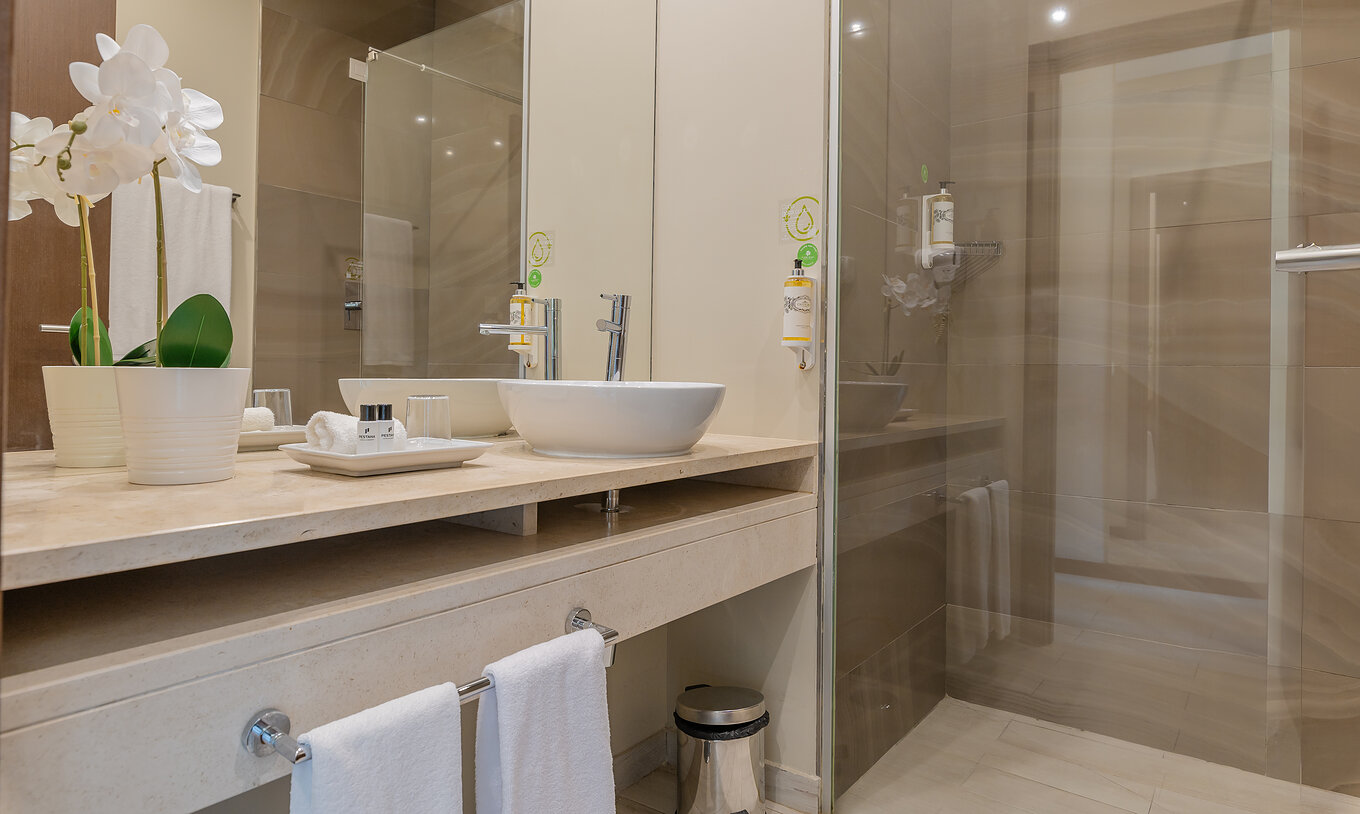 La Suite Garden del Pestana Alvor Park tiene un baño con bañera y lavabo con un jarrón de flores