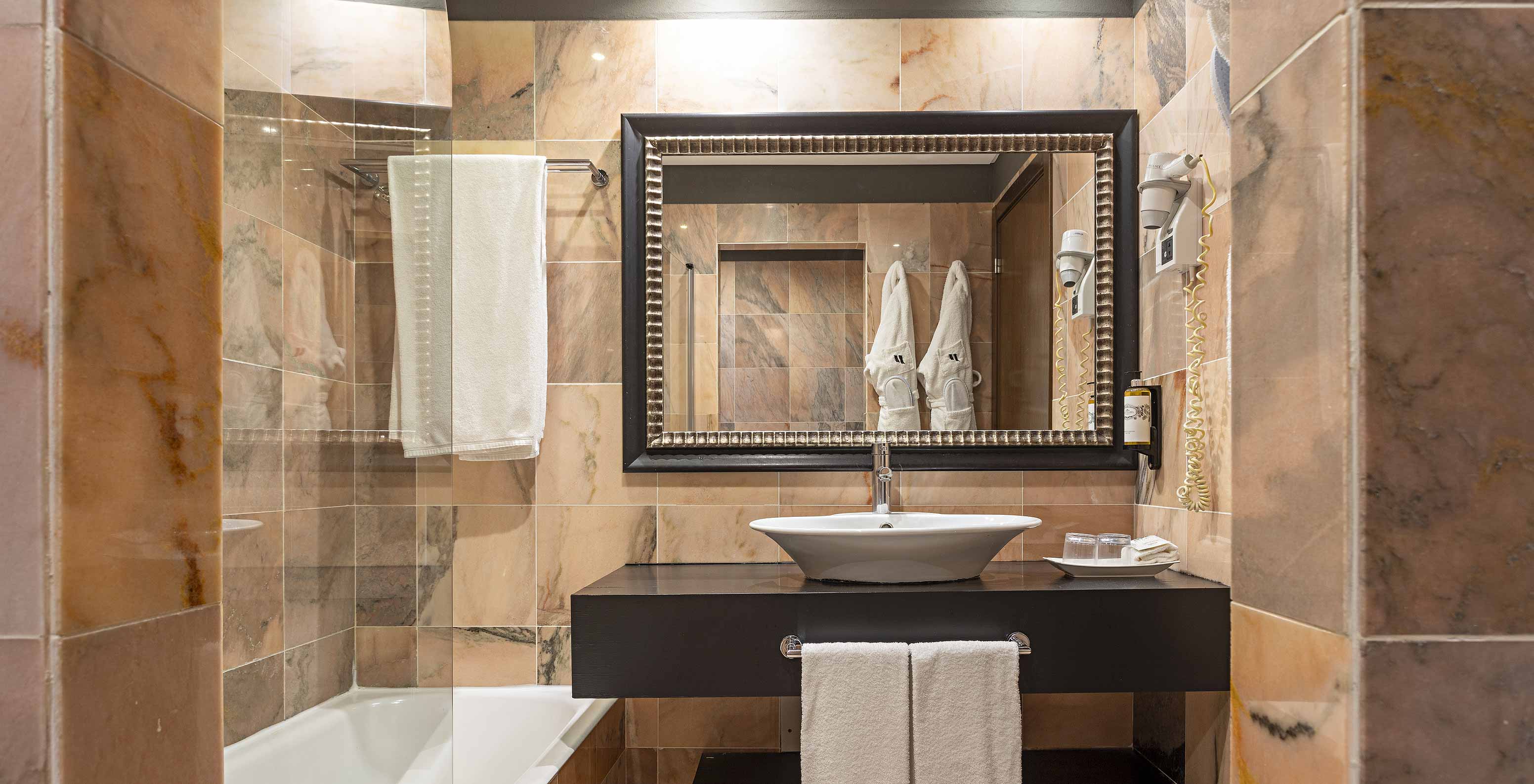 La Suite Cliff T1 en Pestana Alvor Praia tiene un baño con una bañera, dos albornoces y un secador de pelo