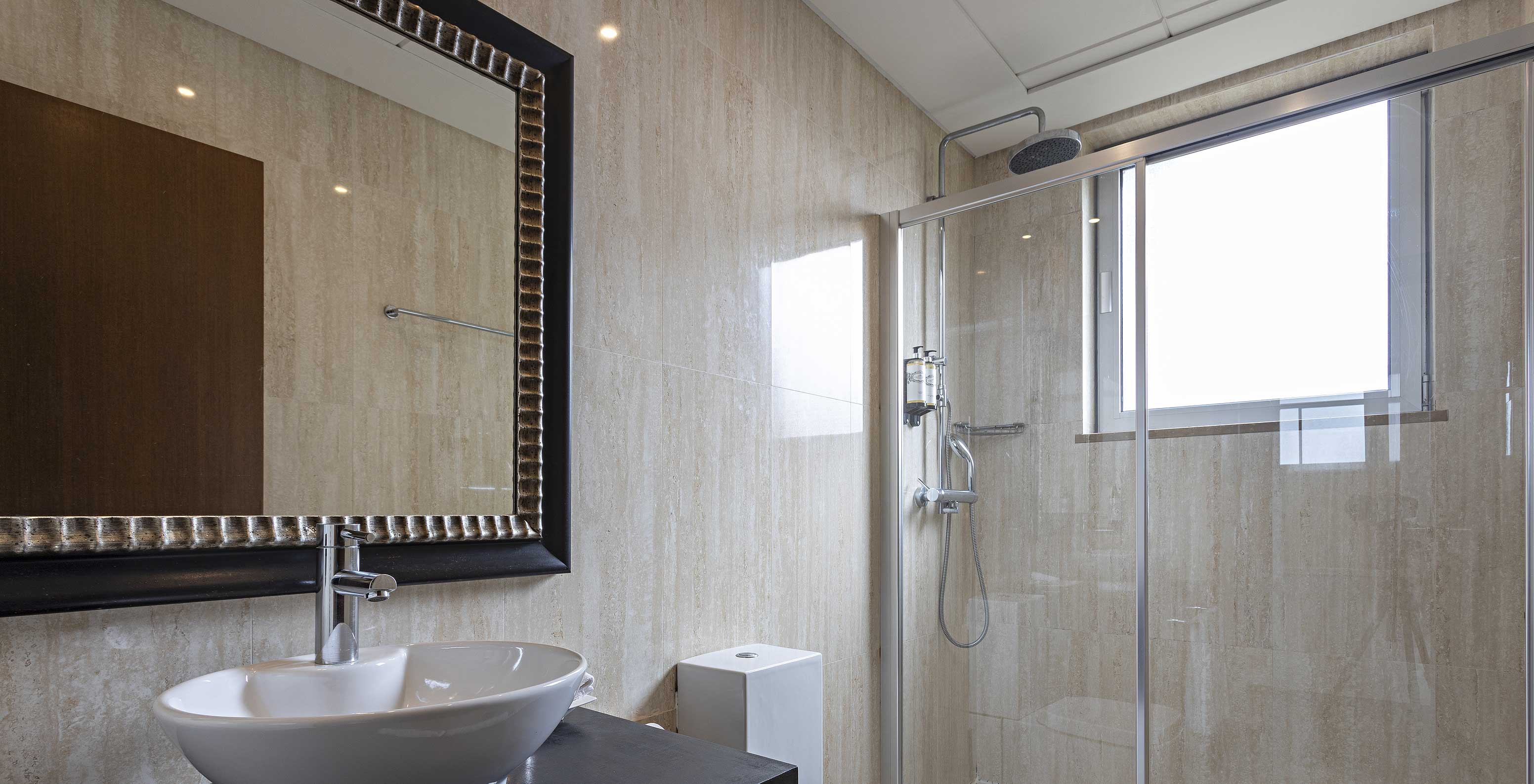 La Cliff Suite T2 en Pestana Alvor Praia tiene un baño moderno con una ventana, una ducha, un lavabo y un espejo