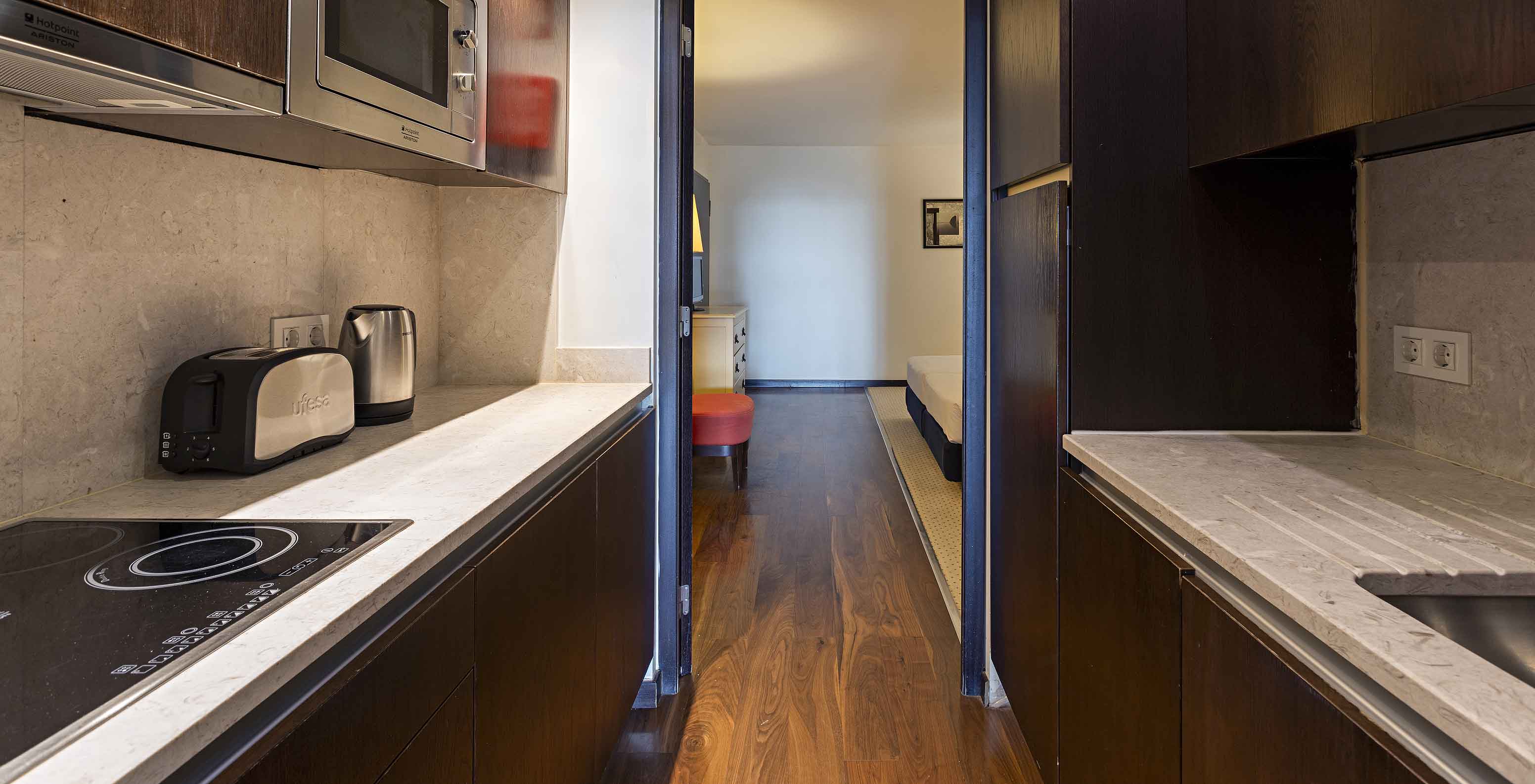 La Cliff Suite T2 en Pestana Alvor Praia tiene una cocina equipada en madera oscura y piedra, con una estufa y un microondas