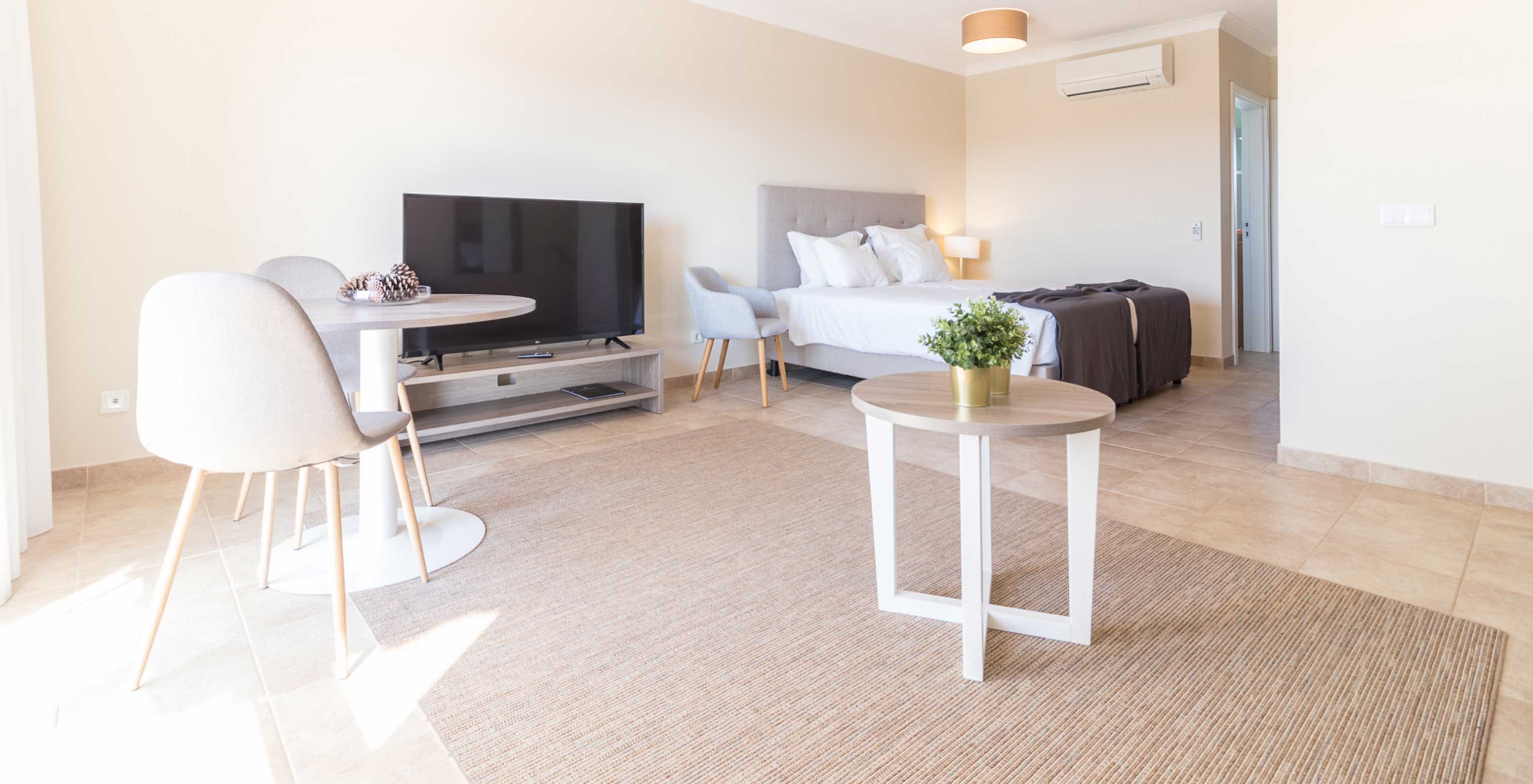 El estudio en Pestana Gramacho Residences es moderno con cama, TV, mesa y decoración minimalista