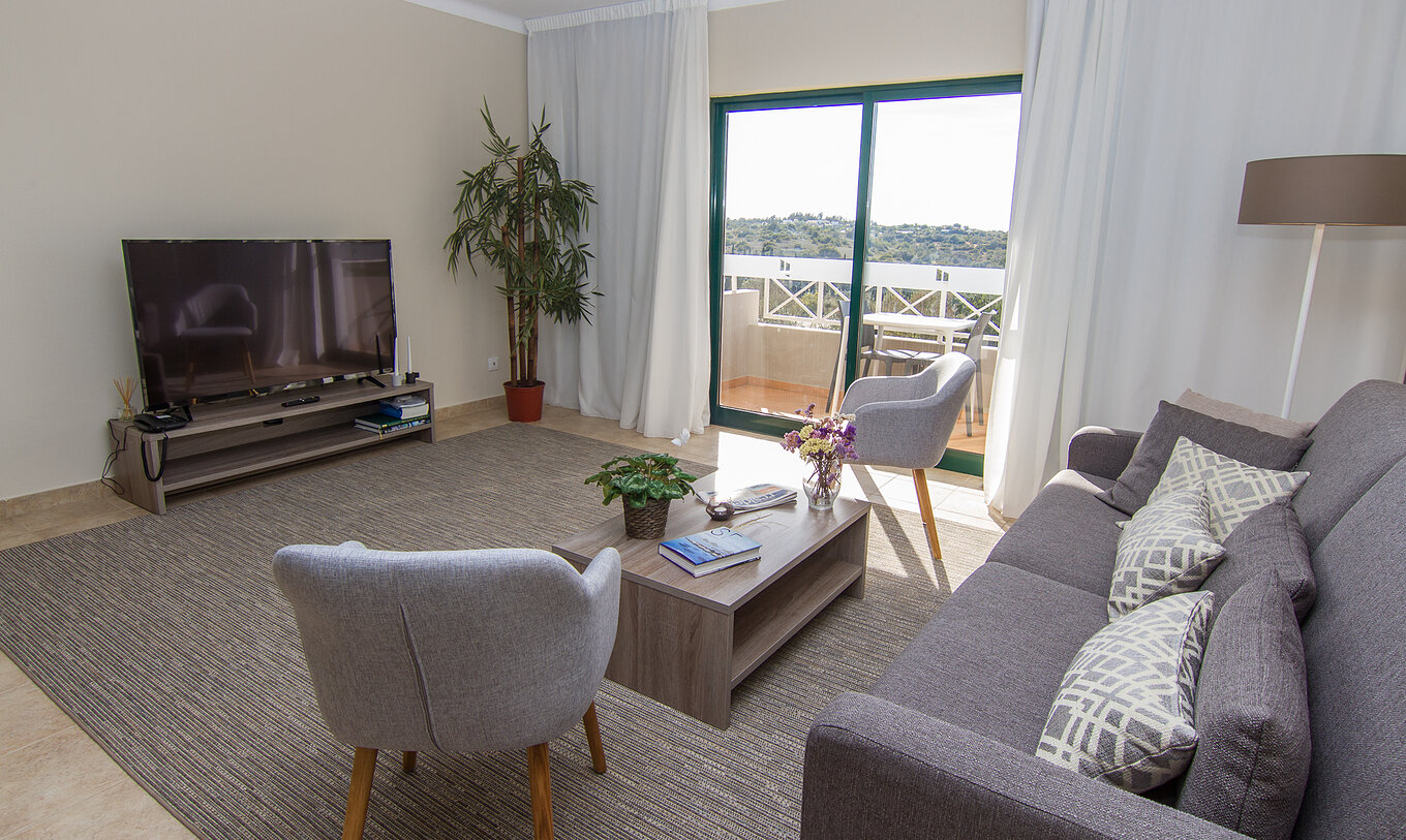 La Villa V3 del Pestana Gramacho Residences tiene una sala de estar con sofás, televisor y una ventana con balcón