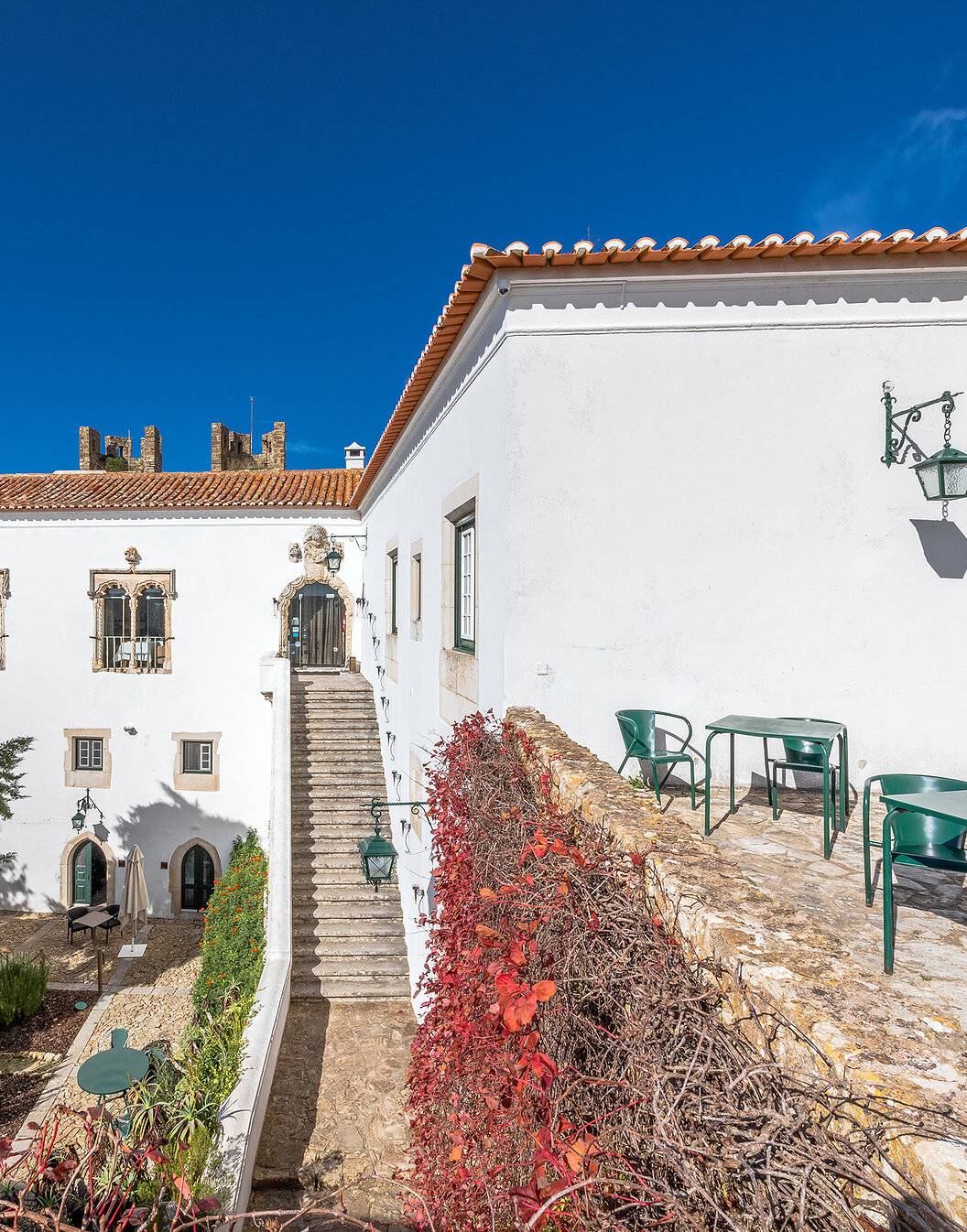 Vista exterior de la fachada de Pousada Castelo Óbidos, con sus jardines, sillas y mesas alrededor